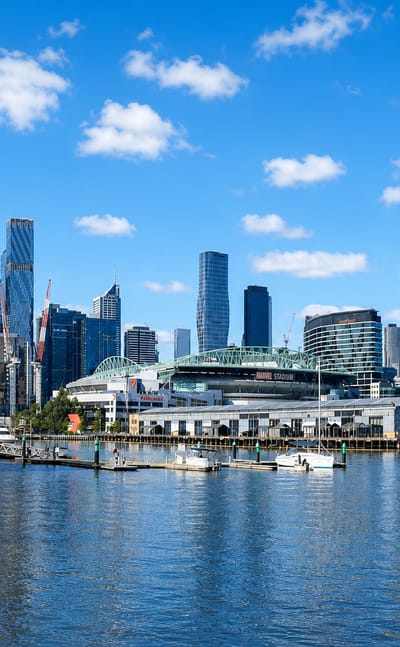 Melbourne's Docklands waterfront and CBD skyline across the harbour under a clear blue sky