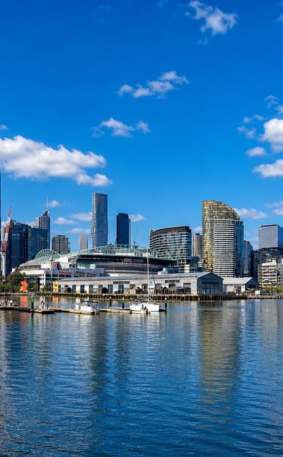 Melbourne Docklands waterfront promenade with the city skyline and stadium across the harbour.