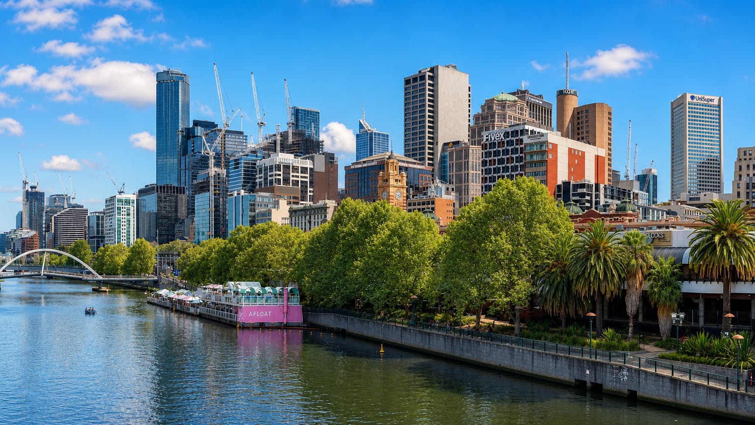 Melbourne city centre skyline along the Yarra River, with the Southbank promenade, plane trees and a pedestrian bridge
