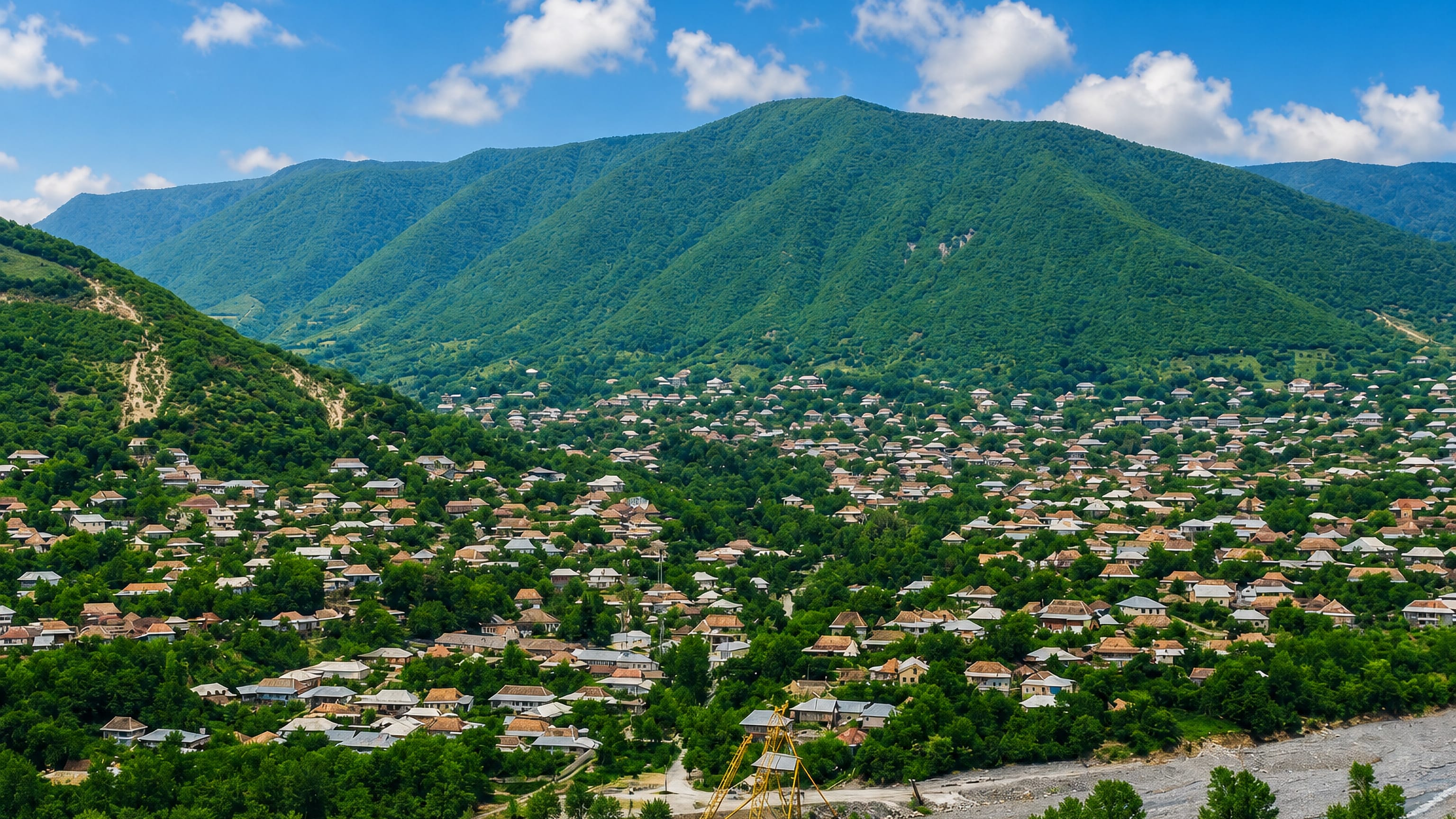 Tiled-roof houses of Sheki spreading up a valley below the forested Greater Caucasus foothills, Azerbaijan.
