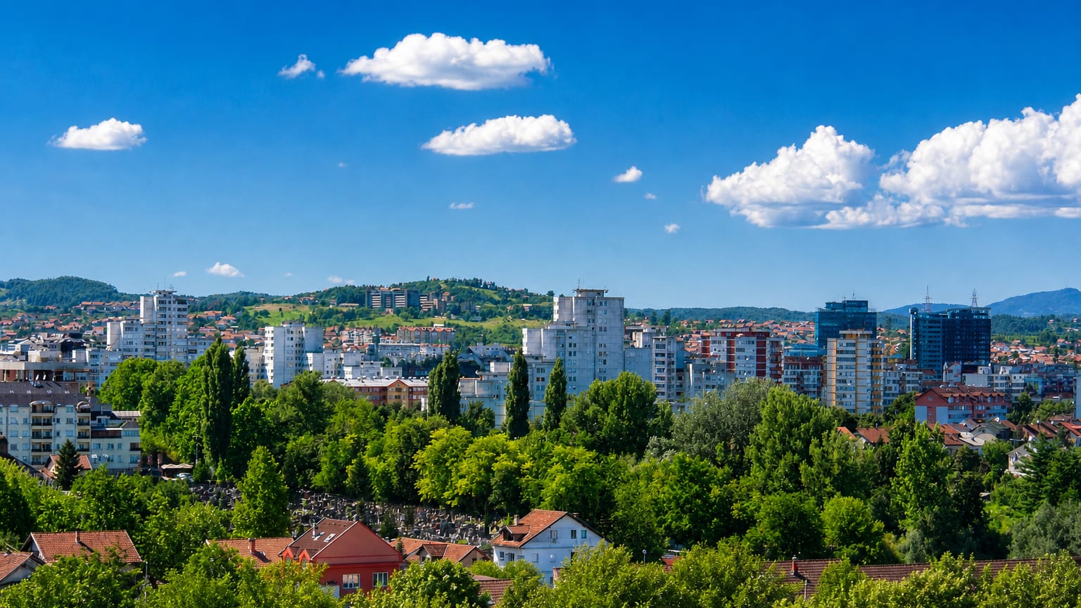 Banja Luka, Bosnia and Herzegovina, with white apartment blocks and red-roofed houses among green trees.