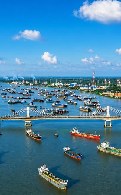 Aerial view of Chattogram's Karnaphuli River port, crowded with cargo ships beside a cable-stayed bridge, Bangladesh.