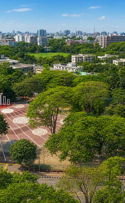 Aerial view of the Shaheed Minar monument amid greenery with the central Dhaka skyline behind