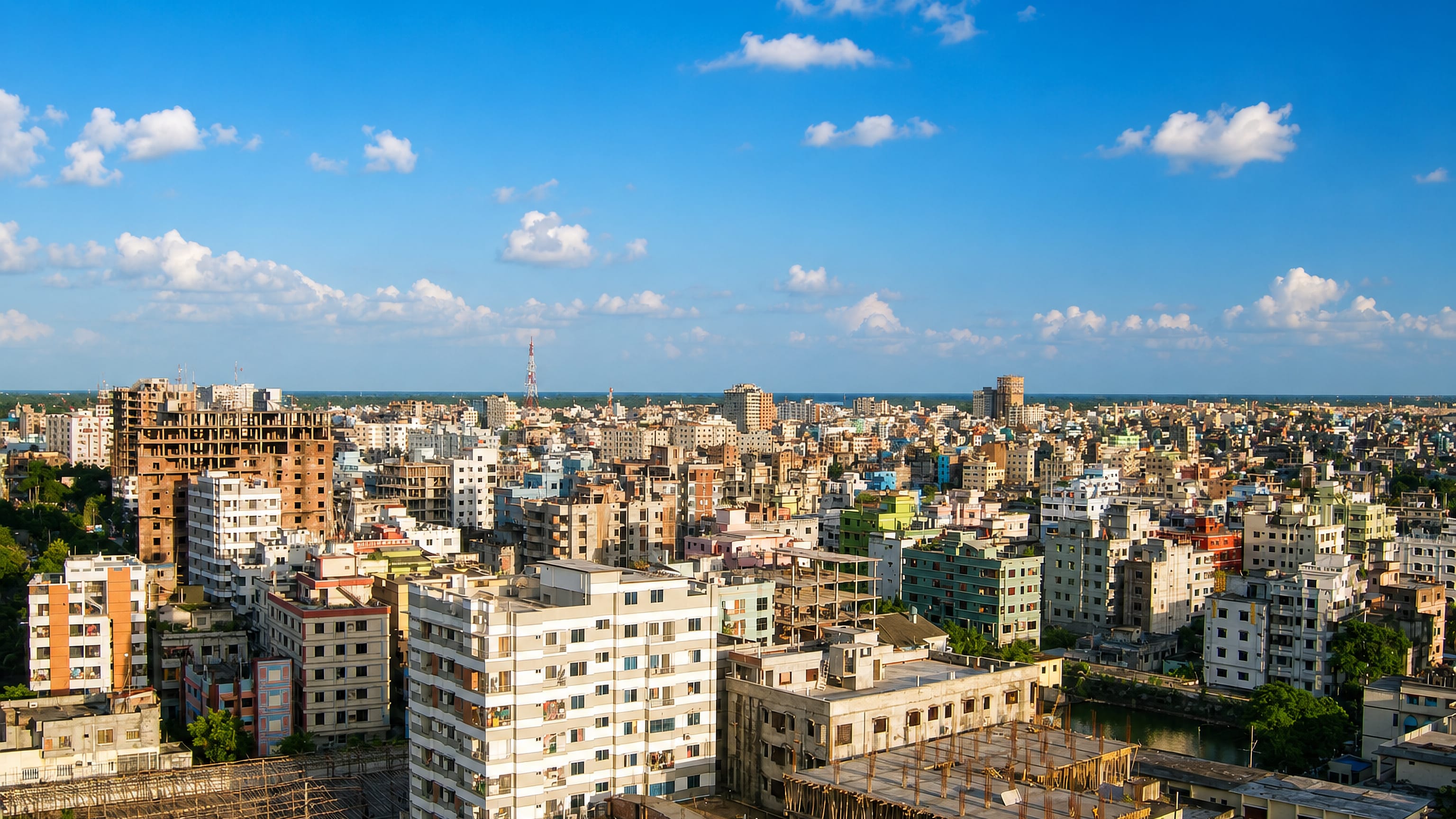 Narayanganj, Bangladesh, from a rooftop: closely packed mid-rise blocks and construction frames beside a canal.