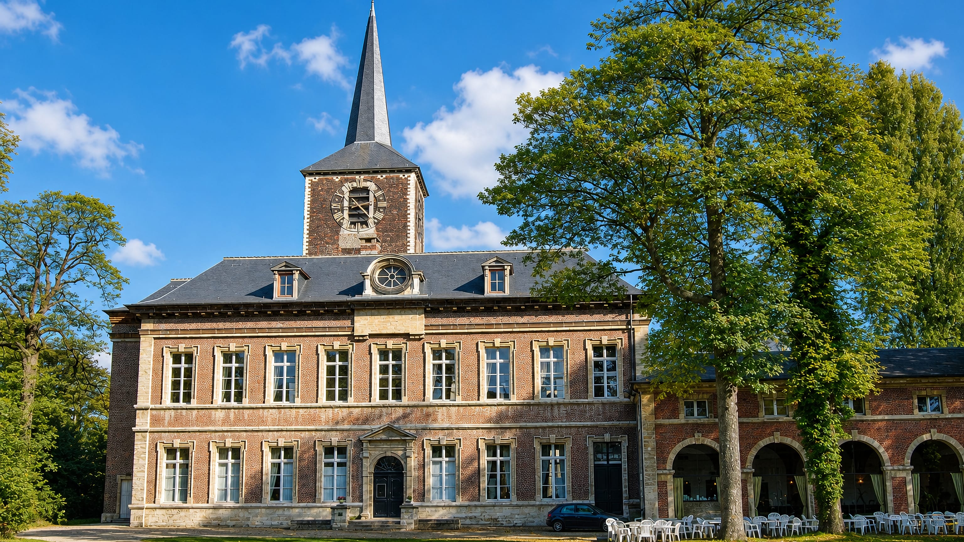 Brick abbey buildings and a church spire in parkland at Forest, a southern municipality of Brussels