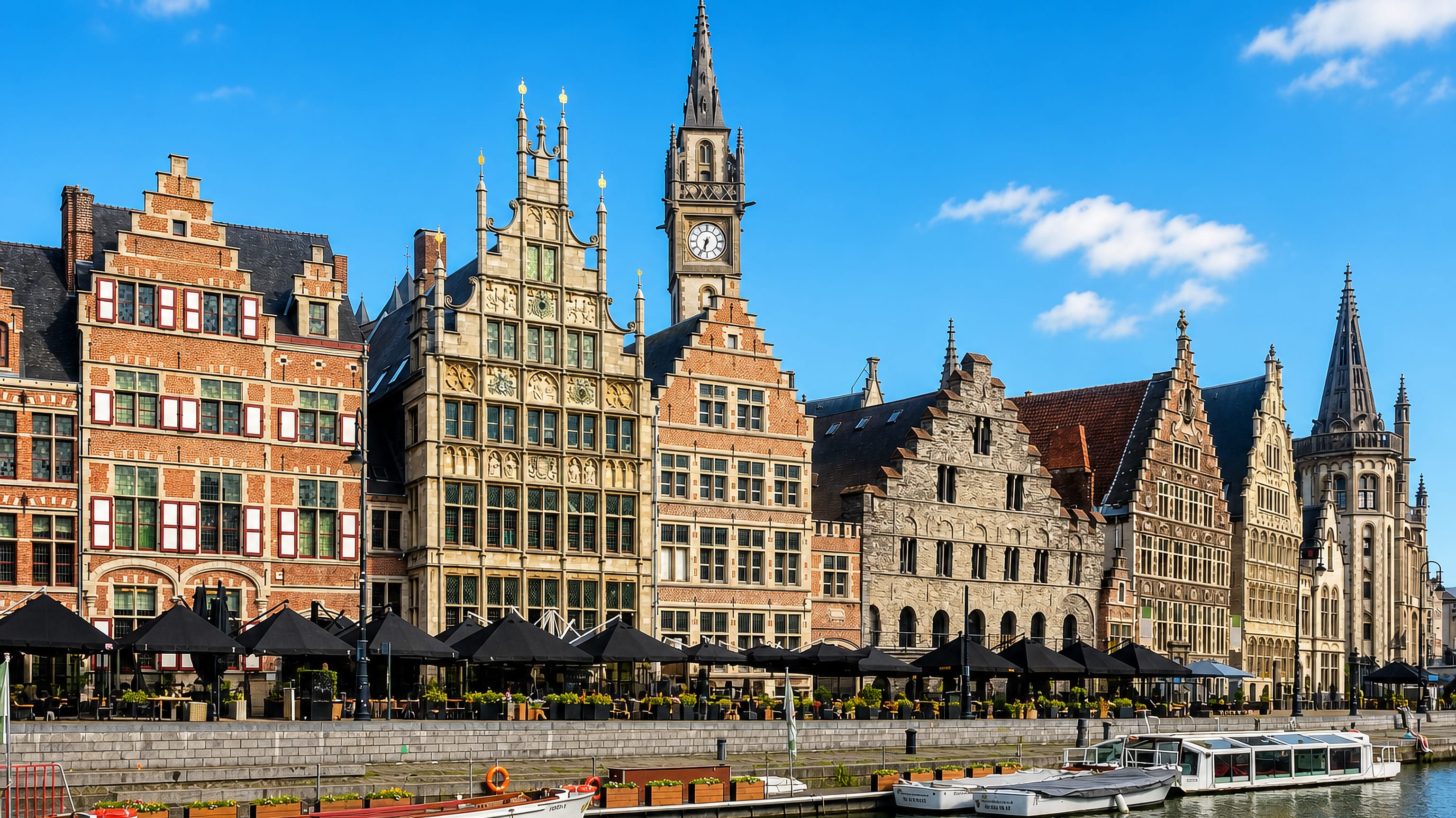 Medieval guild houses and the post office clock tower along the Graslei quay on the Leie river in Gent, Belgium.