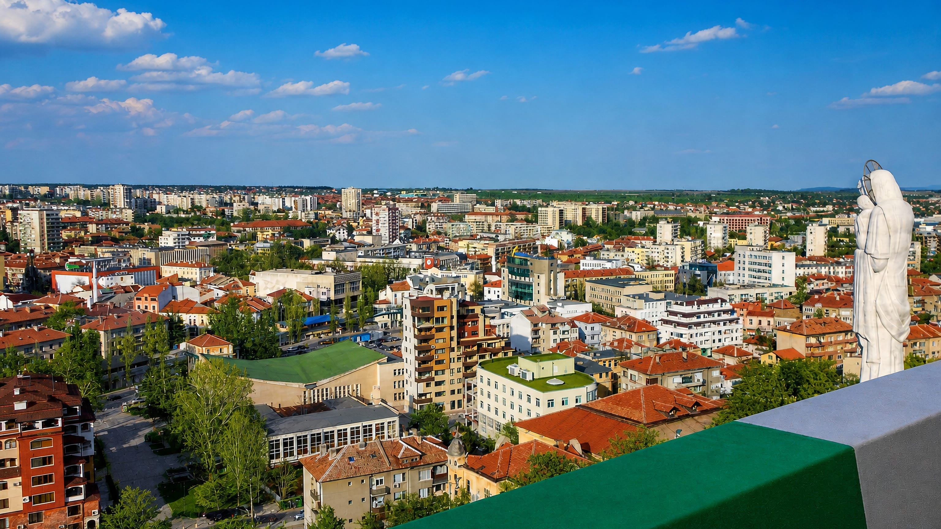 Panorama of Haskovo's red-roofed centre seen past the white Monument of the Virgin Mary statue.