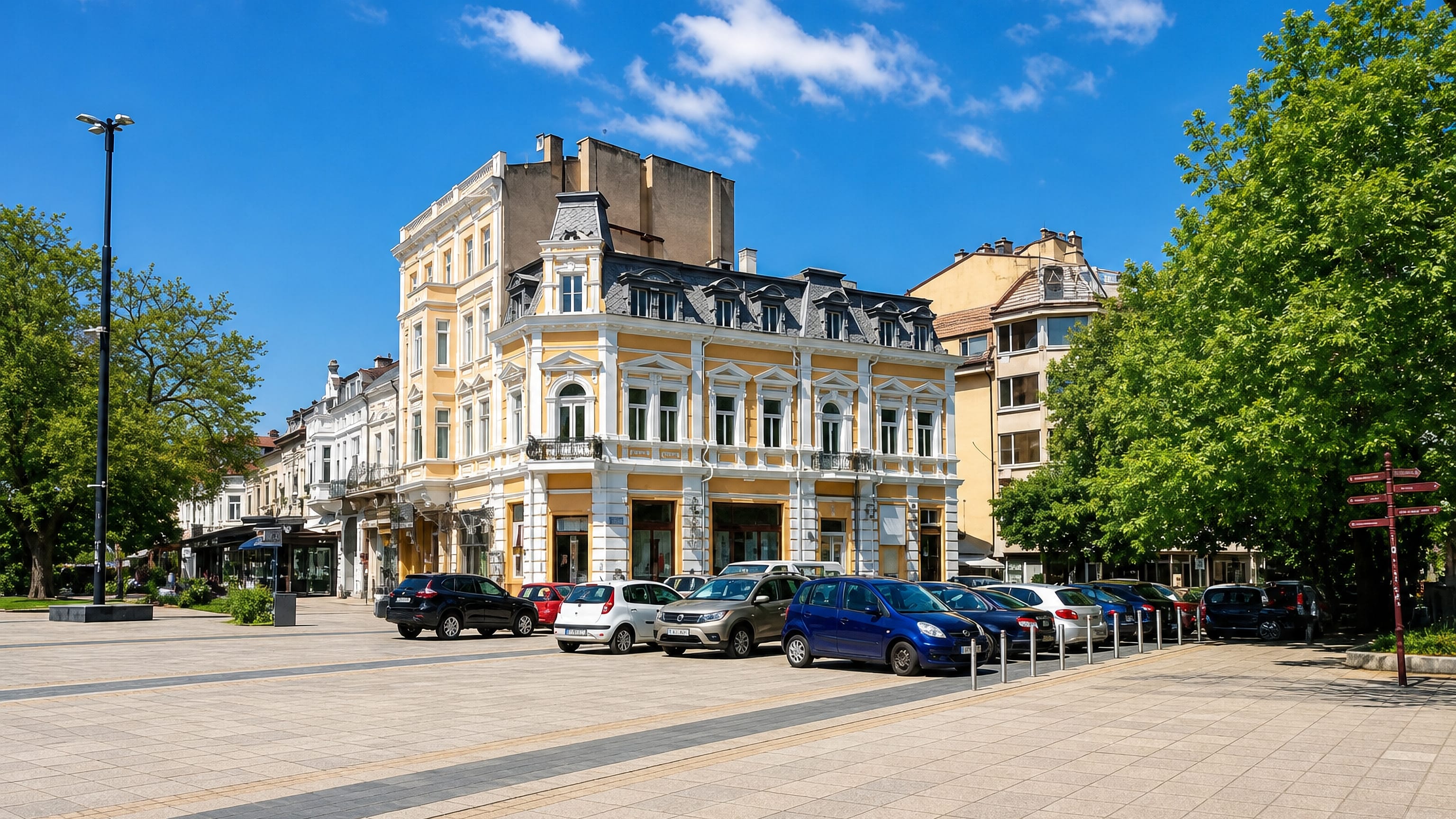 Neo-baroque yellow and white facades lining a wide paved square in Ruse, Bulgaria, under a clear sky.