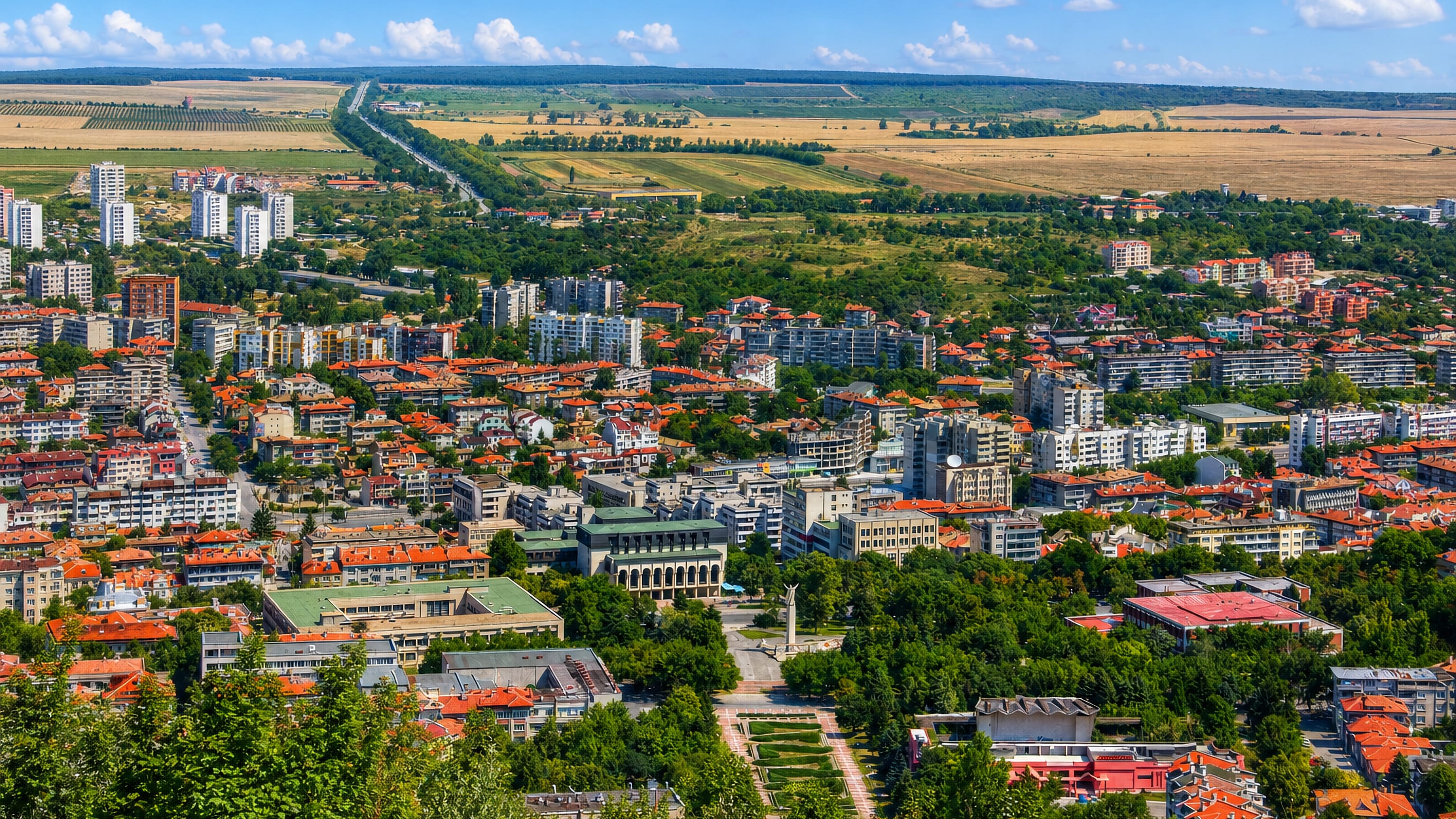 Shumen, Bulgaria, seen from the plateau: red-tiled roofs and apartment blocks against surrounding farmland.