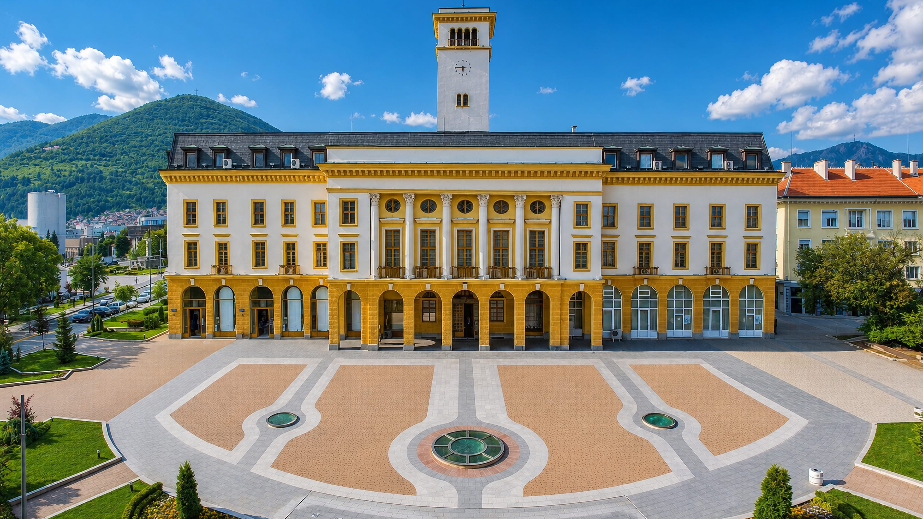 Sliven's yellow-and-white town hall and clock tower on its paved square, with the Blue Rocks rising behind.