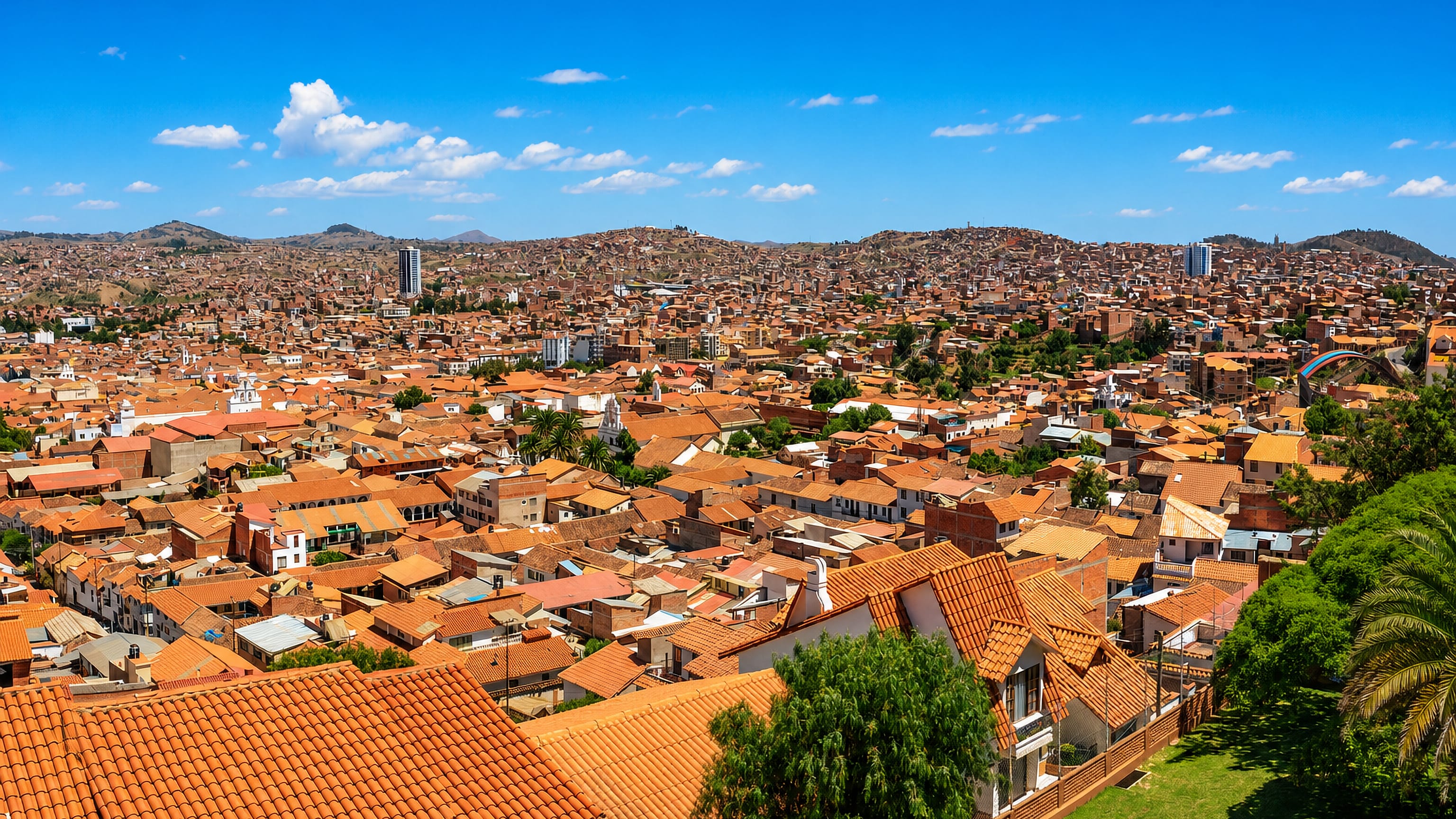 Sucre's terracotta-roofed colonial cityscape across a valley, white church towers rising toward surrounding hills.