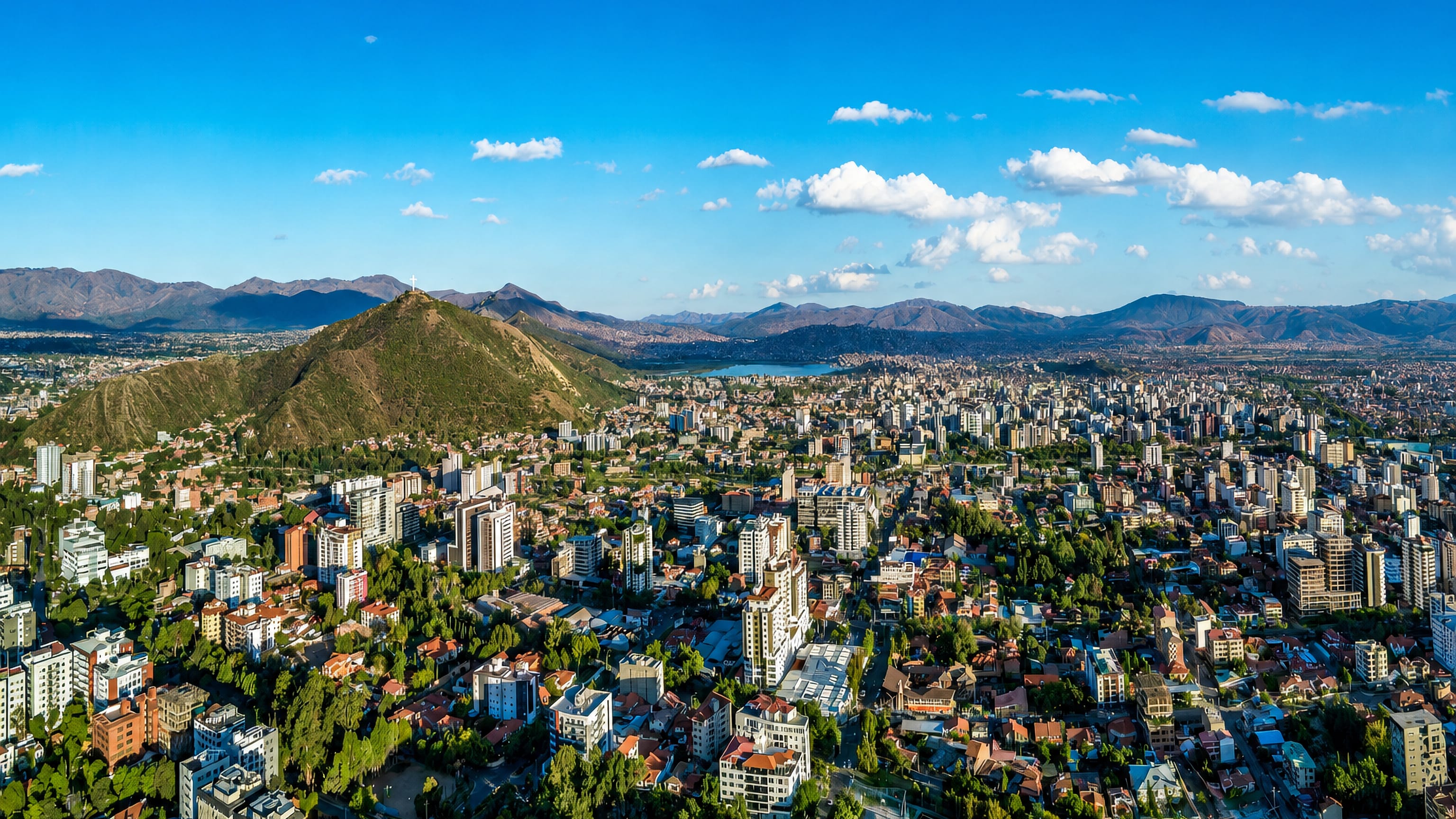 Aerial view of Cochabamba, Bolivia, spreading across its Andean valley beneath the cross-topped San Pedro hill.