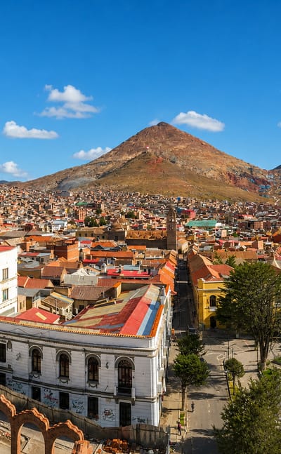 Potosi's terracotta rooftops and colonial plaza below the pyramid-shaped Cerro Rico mountain under a blue sky