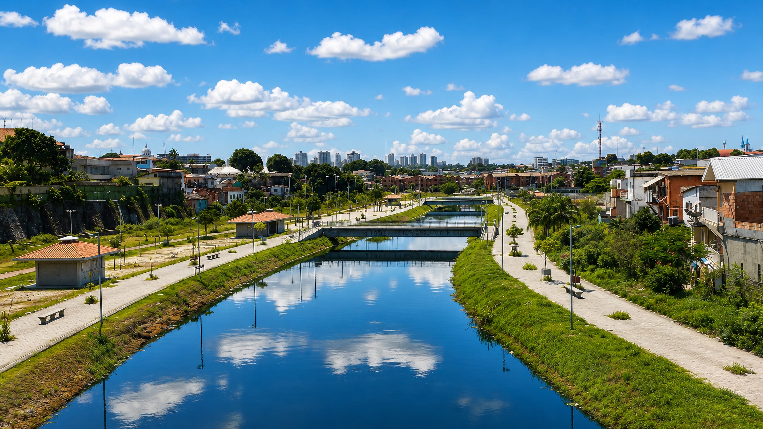 Landscaped canal park lined with walkways and low houses below the Manaus skyline, Cachoeirinha, Brazil.