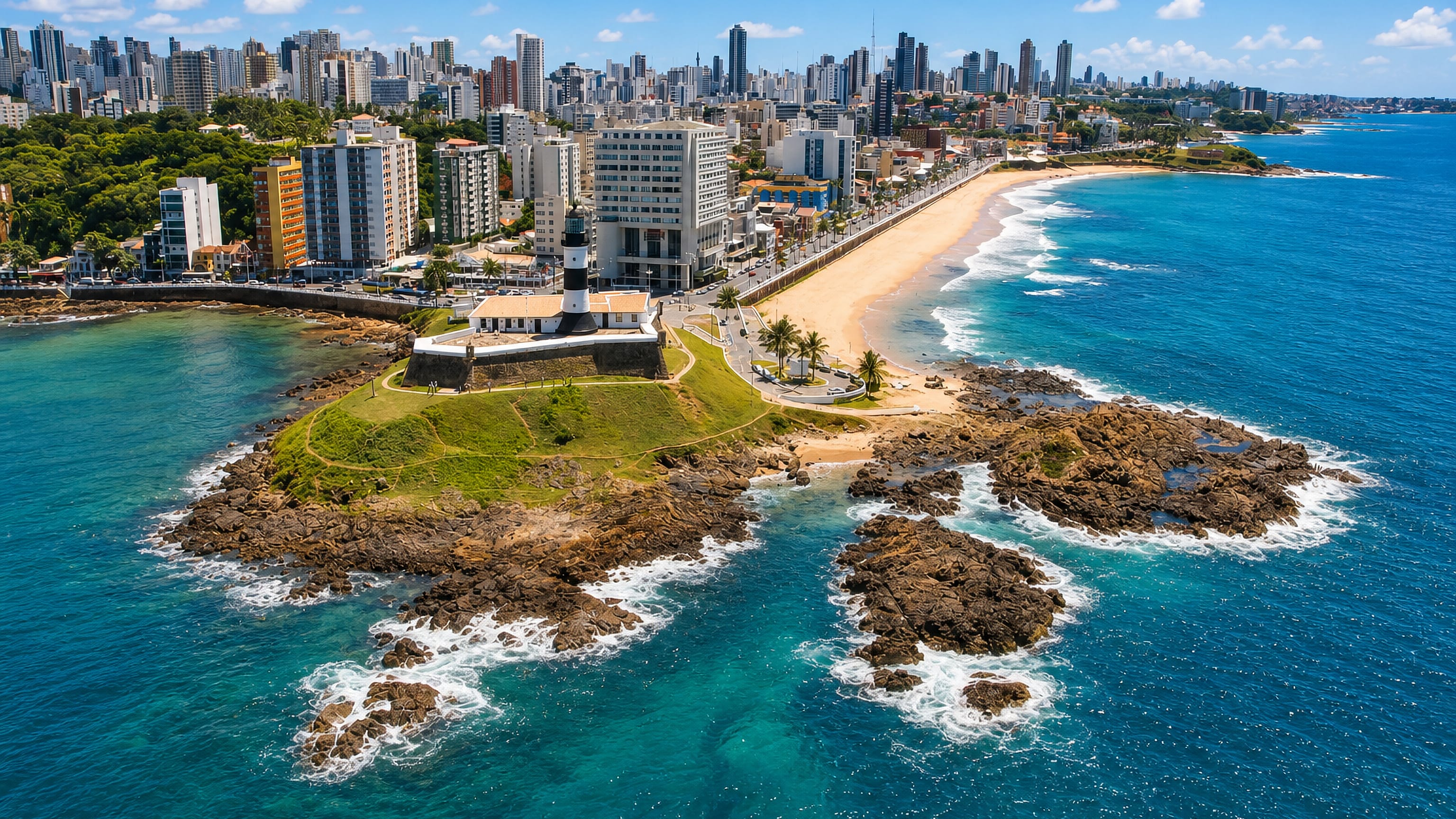 The Barra lighthouse and fort on the rocky point below Salvador's high-rise skyline in Barra, Bahia.