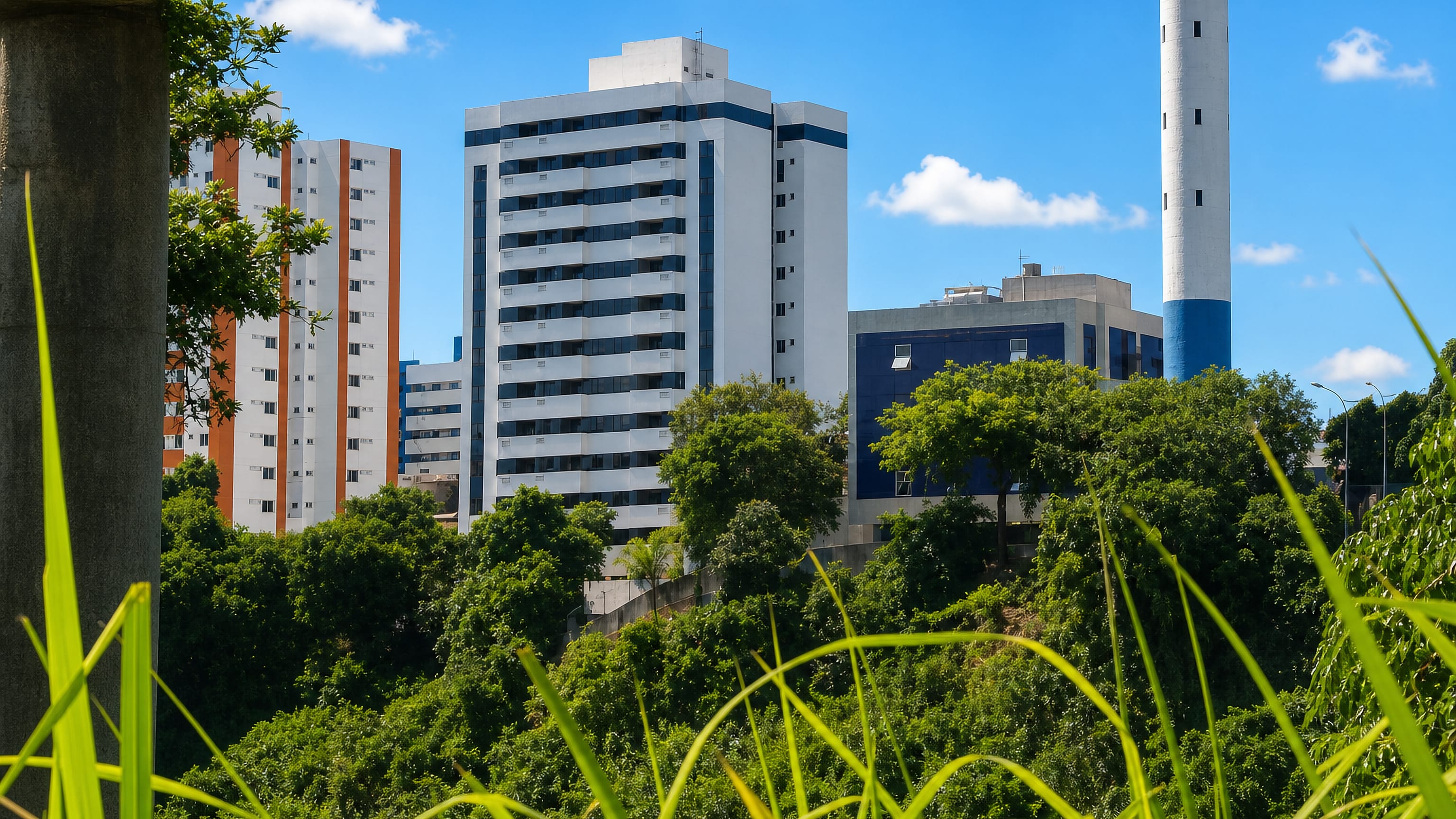 Apartment towers and a water tower above the greenery of Cabula in Salvador, seen from beneath a viaduct.