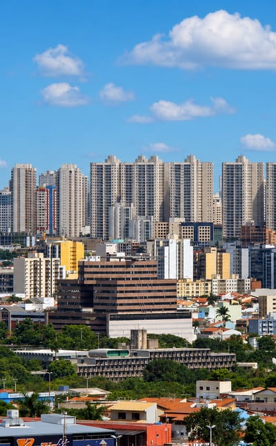 Skyline of residential and commercial high-rise towers in Taguatinga, Brasília, above low houses and greenery.