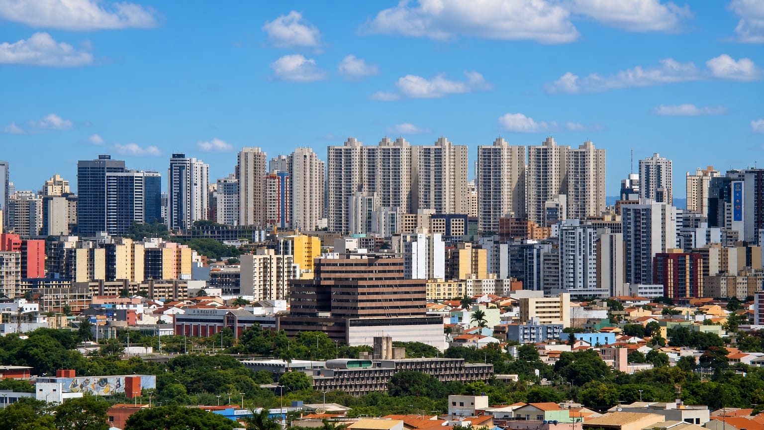 Skyline of residential and commercial high-rise towers in Taguatinga, Brasília, above low houses and greenery.