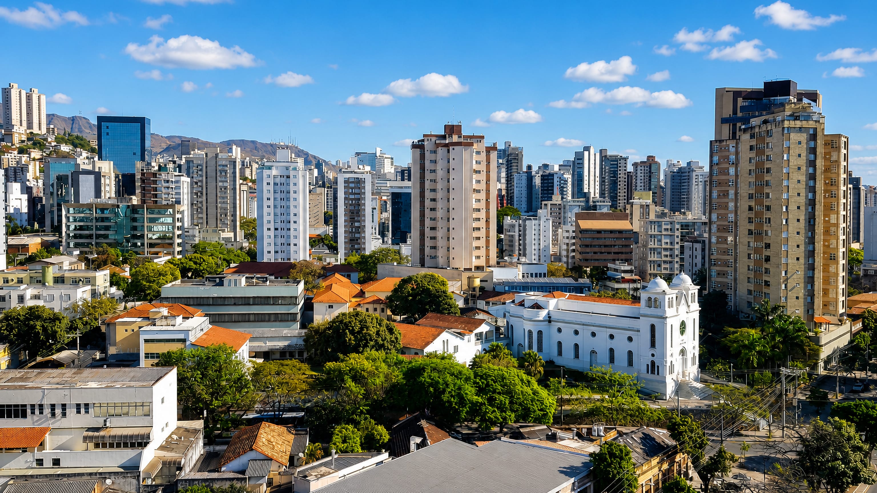 High-rises, red-tiled roofs and a white church in Santa Efigenia, Belo Horizonte, below the Serra do Curral.