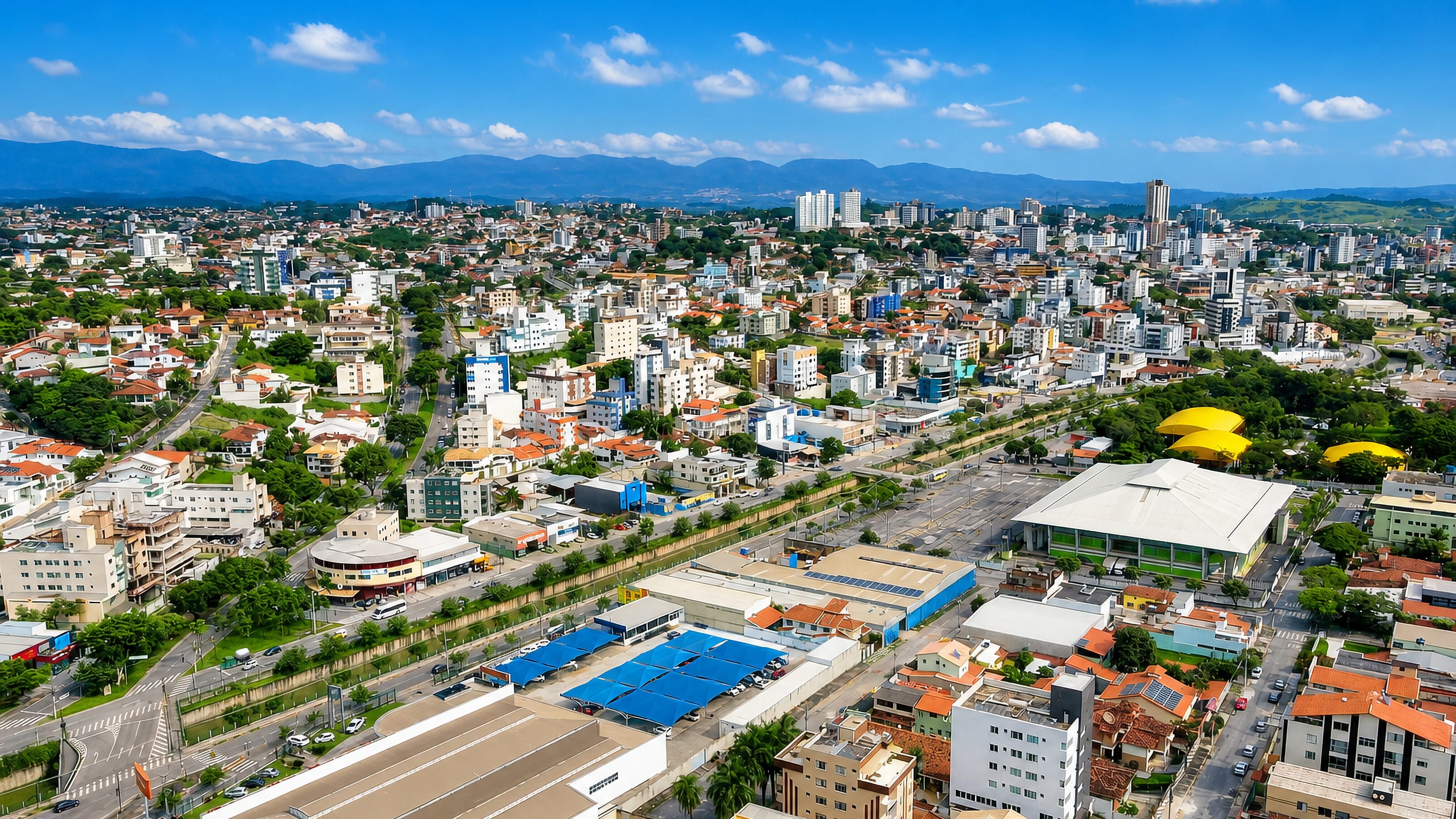 Betim, Minas Gerais, from the air: apartment blocks, warehouses and wooded hills on the horizon.