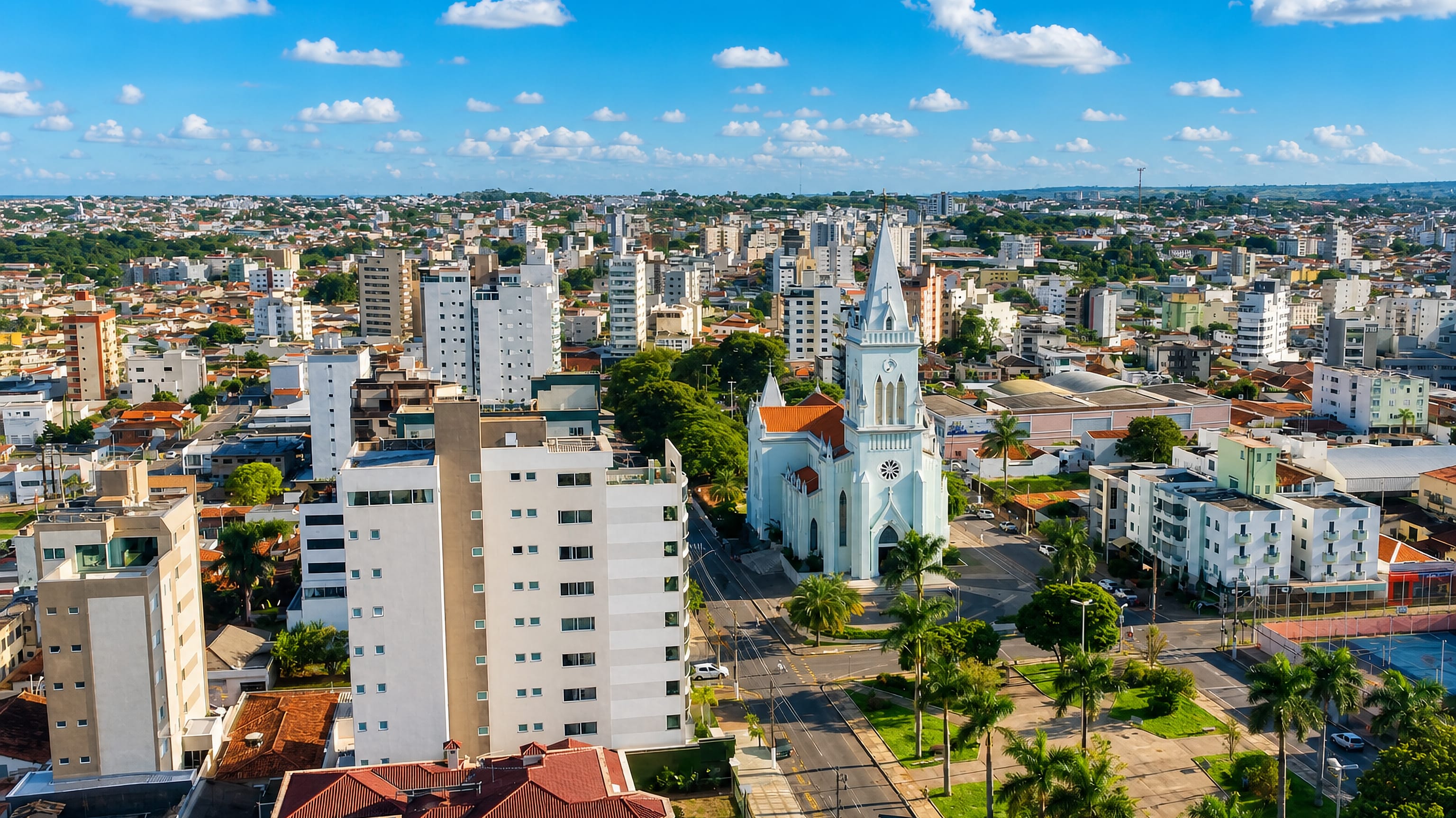 Aerial view of Patos de Minas, Brazil, centred on its pale blue neo-Gothic cathedral and palm-lined square.