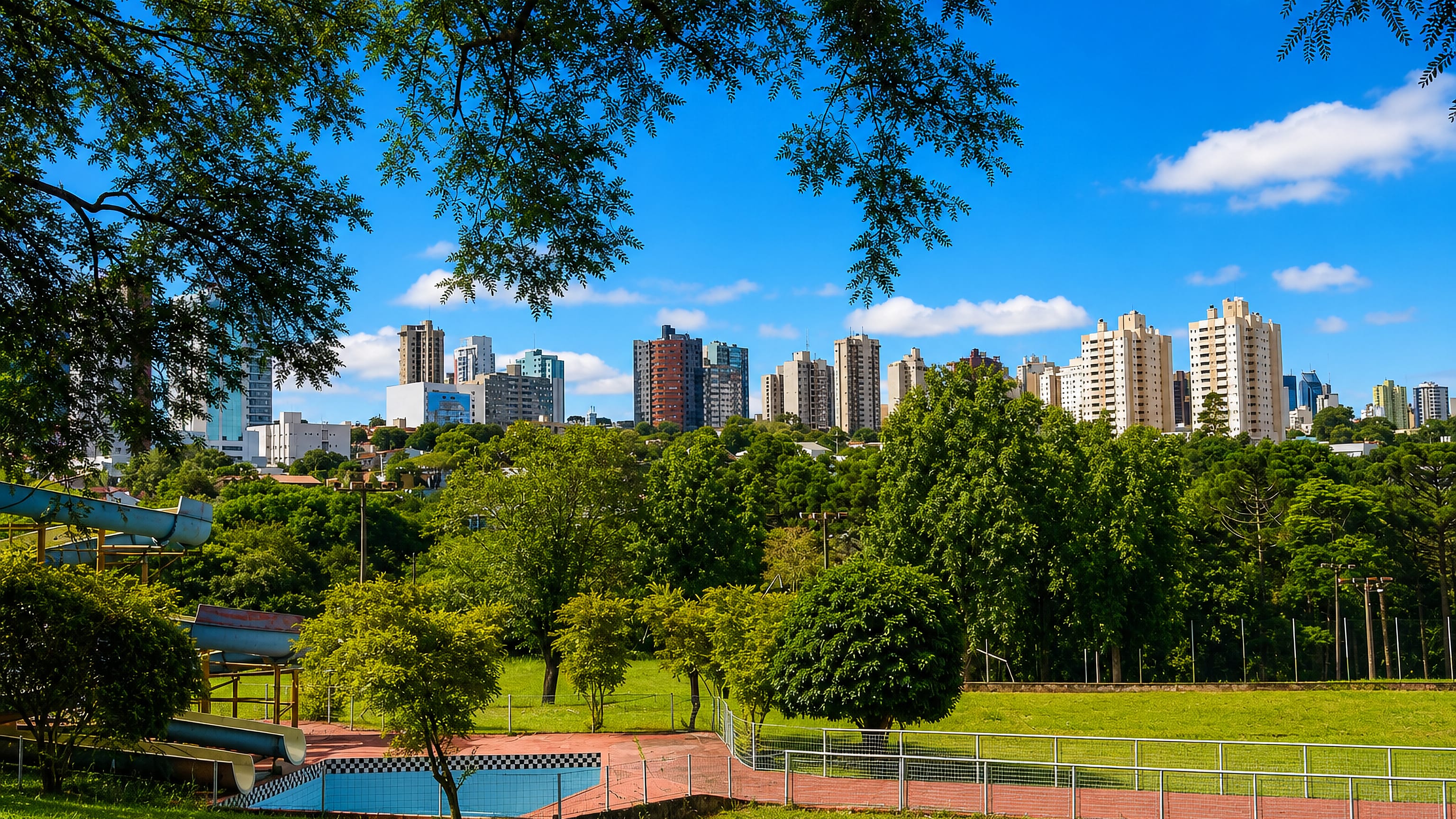 Apartment towers of Cascavel, Paraná, rising above the wooded parkland of the city's lake park.