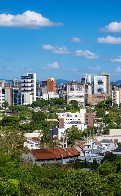Curitiba's modern high-rise skyline rising above leafy green residential neighbourhoods.