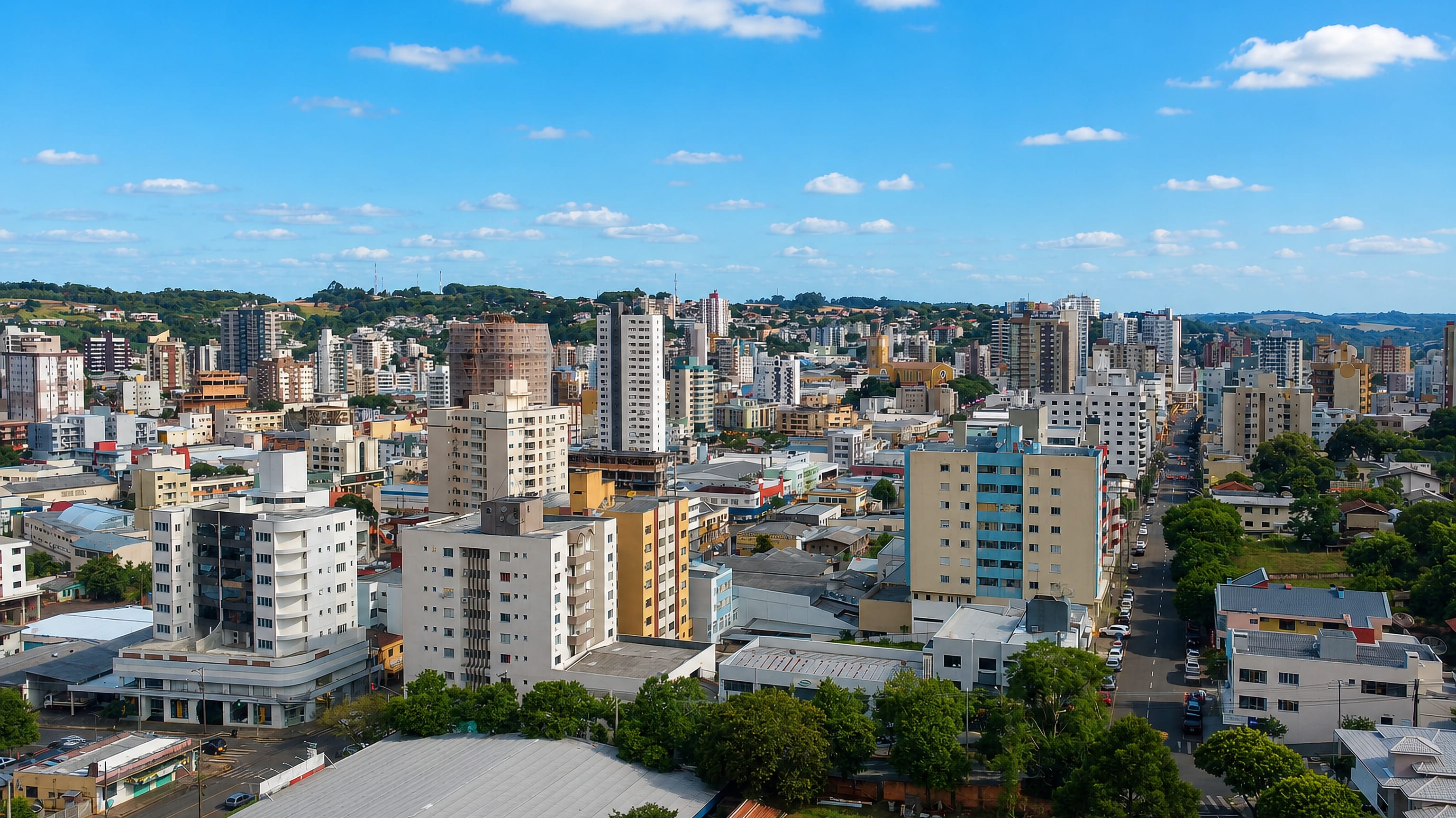 Aerial view of apartment towers and tree-lined avenues among green hills in Pato Branco, Brazil