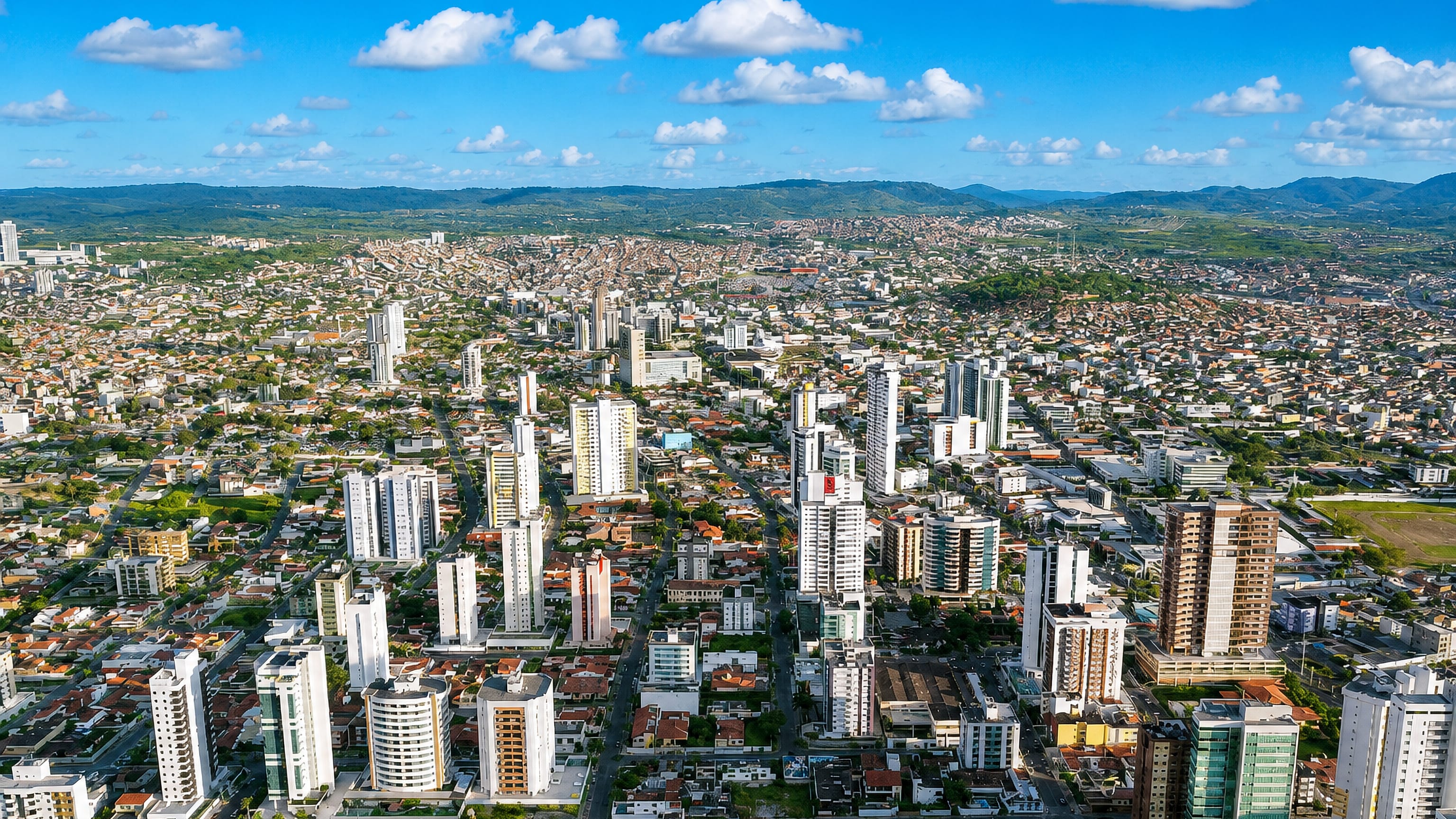 Aerial view of Caruaru's towers and red-tiled rooftops spreading toward the green hills of the Pernambuco agreste.