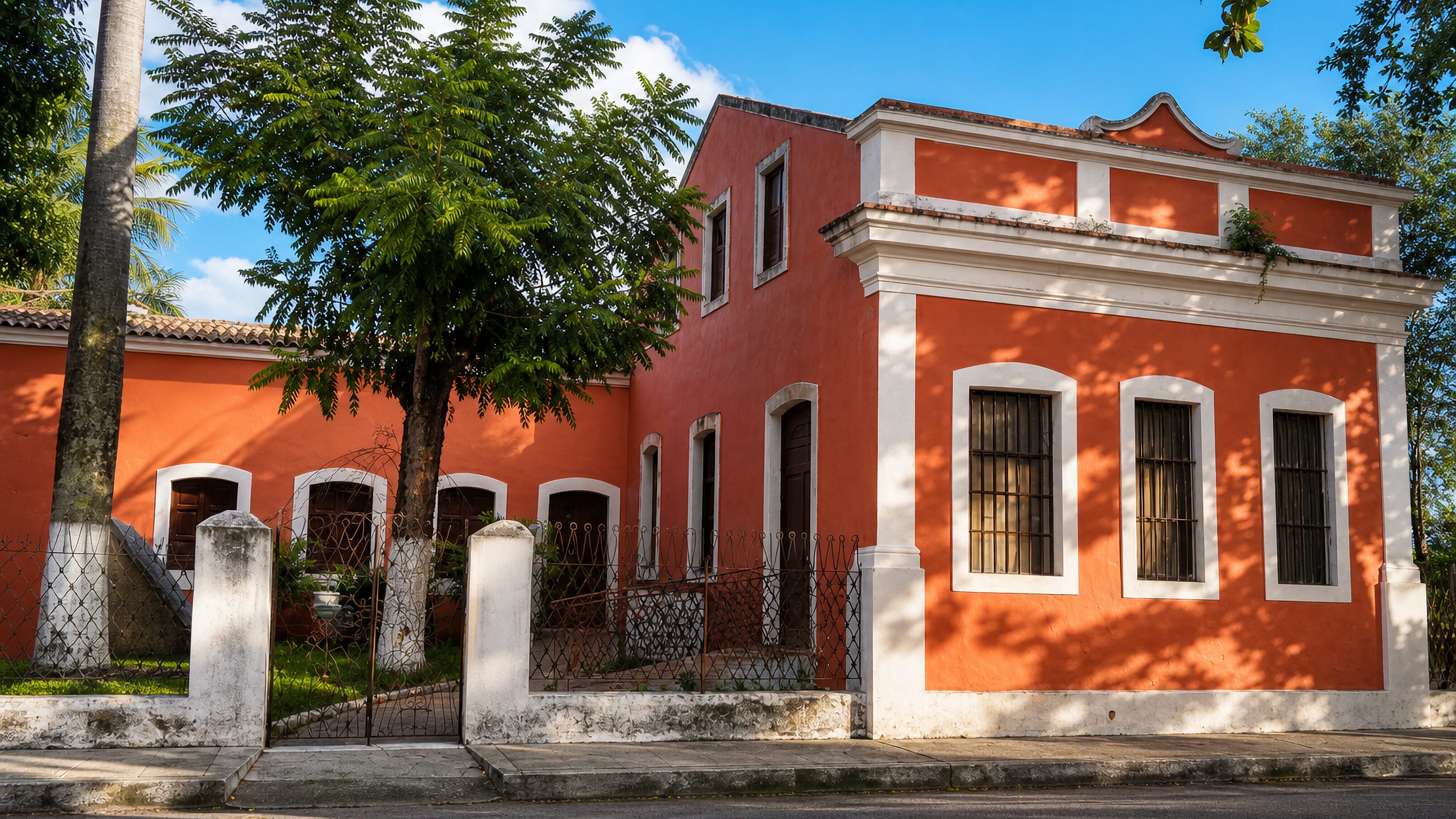 Orange colonial casarão with white trim and shade trees on a quiet street in Poço da Panela, Recife