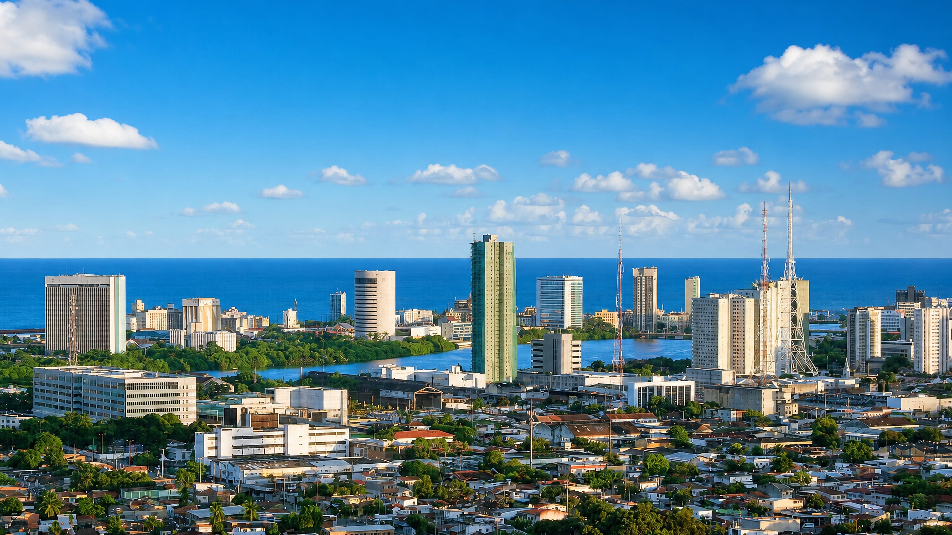 Santo Amaro's high-rises and dense rooftops in Recife, with the Capibaribe river and the Atlantic beyond.