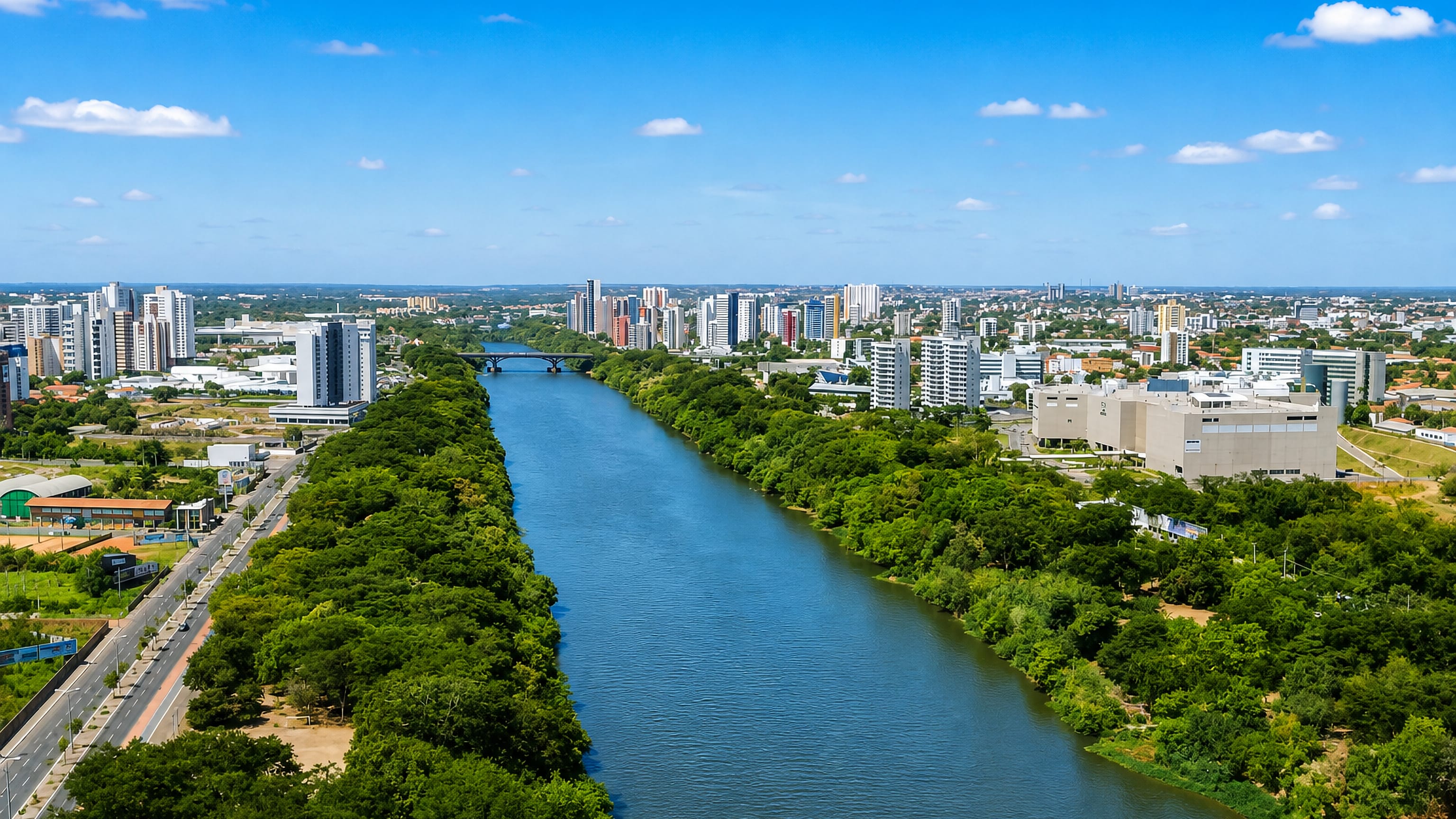 Aerial view of Teresina, Brazil, with high-rise blocks lining the tree-fringed Poti River and a road bridge crossing it.