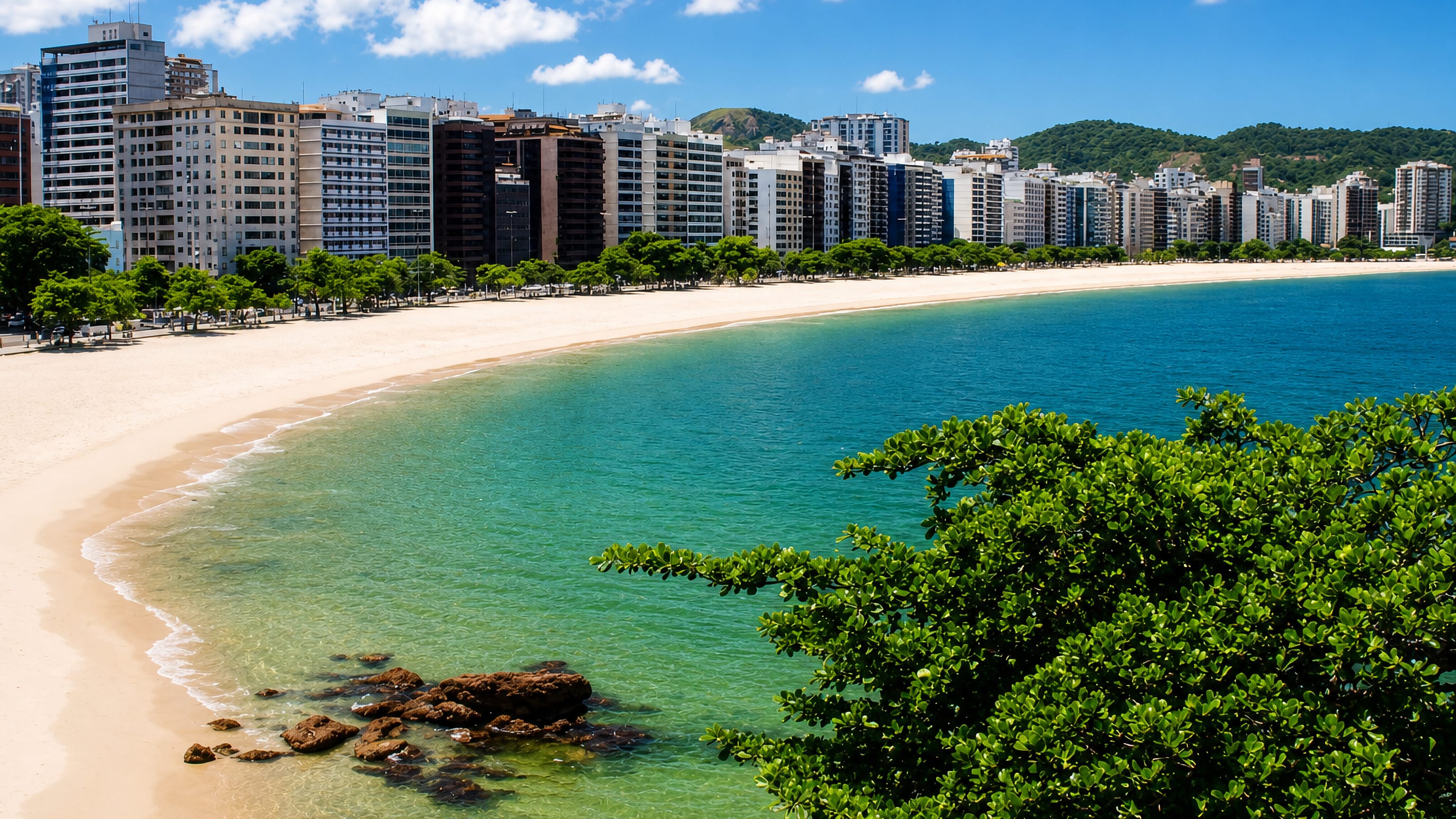The curve of Icarai beach in Niteroi, lined with apartment towers and backed by green hills.