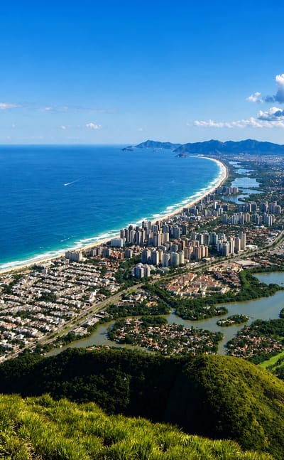 Aerial view of Rio de Janeiro's long curving beach, coastal lagoons and green mountains meeting the Atlantic.