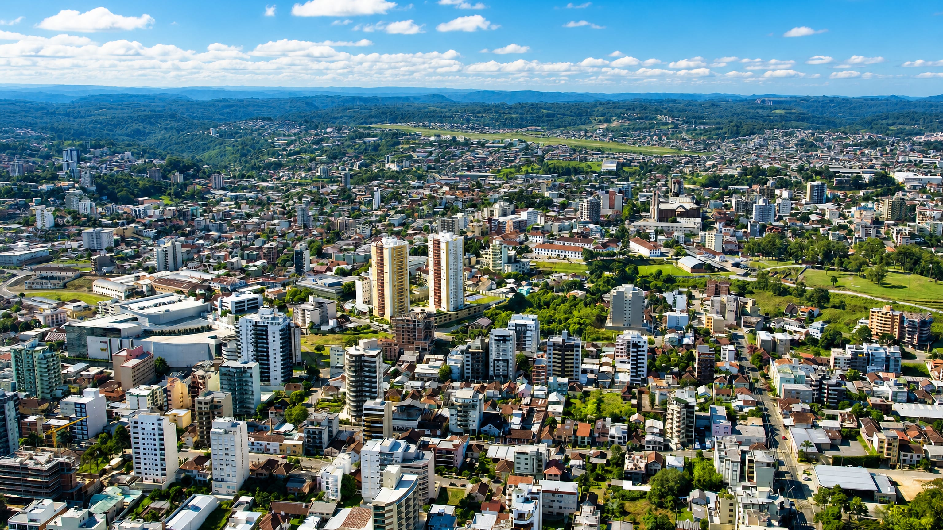 Aerial view over Caxias do Sul, Brazil, with mid-rise apartment blocks and the green hills of Serra Gaucha.