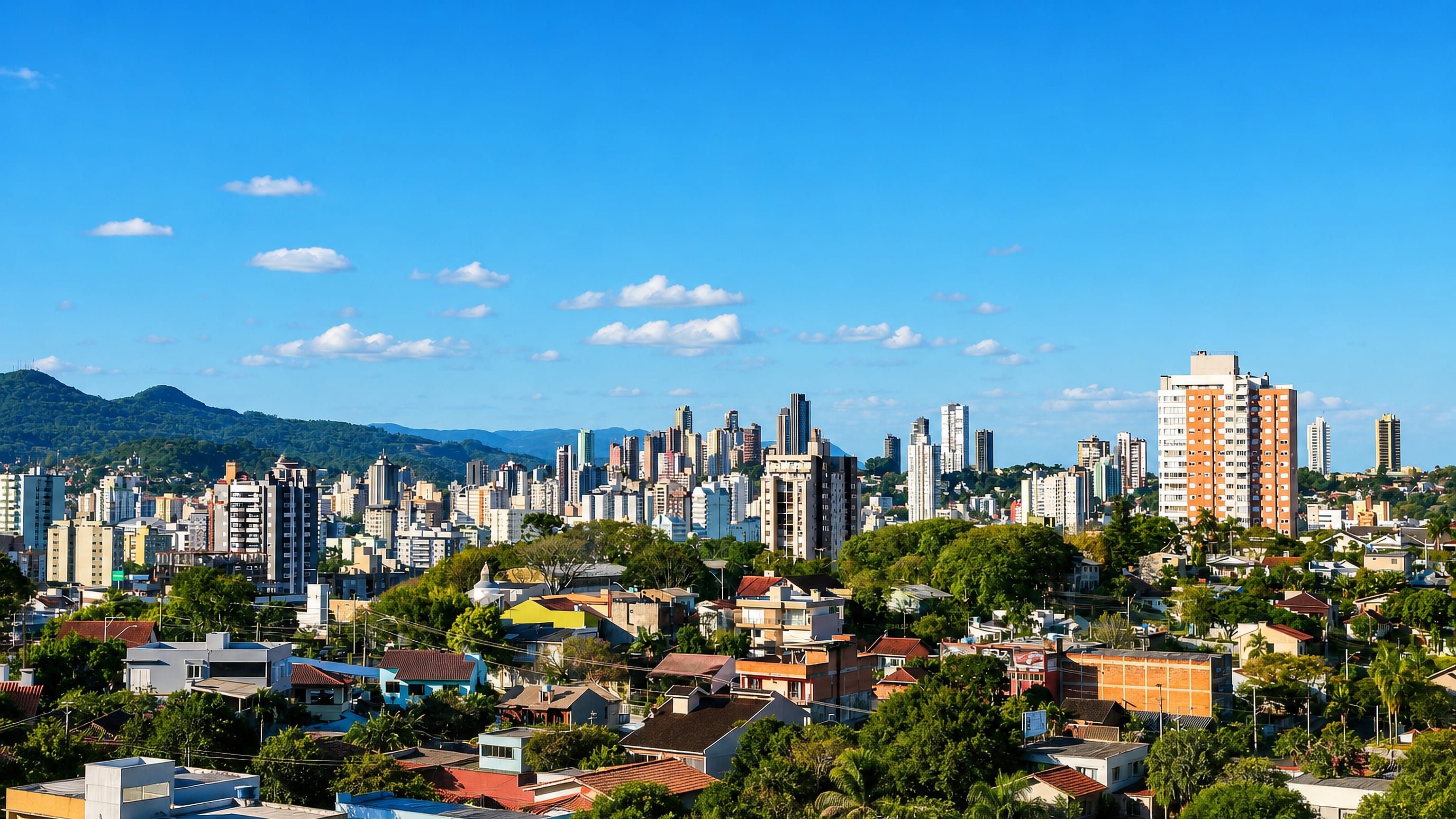 Novo Hamburgo's mid-rise skyline rising above tree-lined residential streets with green hills on the horizon.