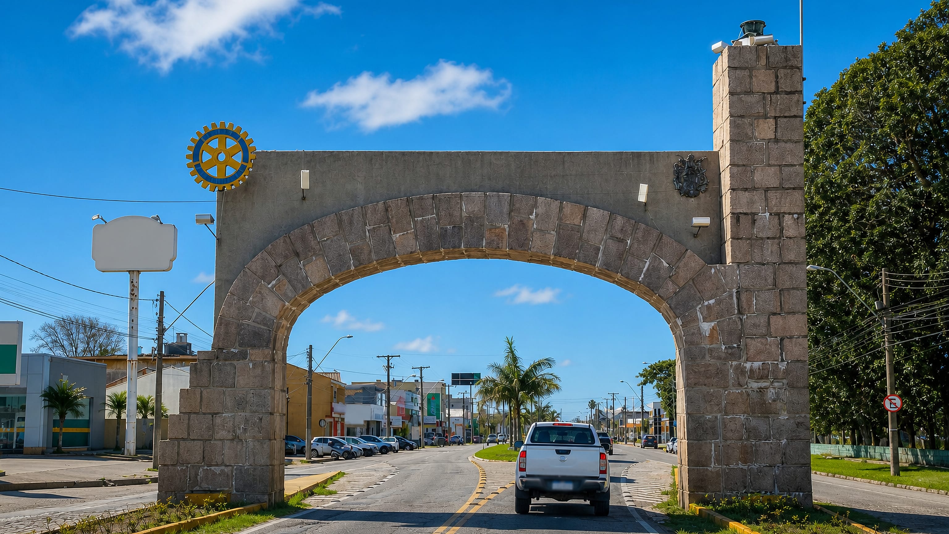 Stone arch gateway spanning a palm-lined avenue at the entrance to Rio Grande, Rio Grande do Sul