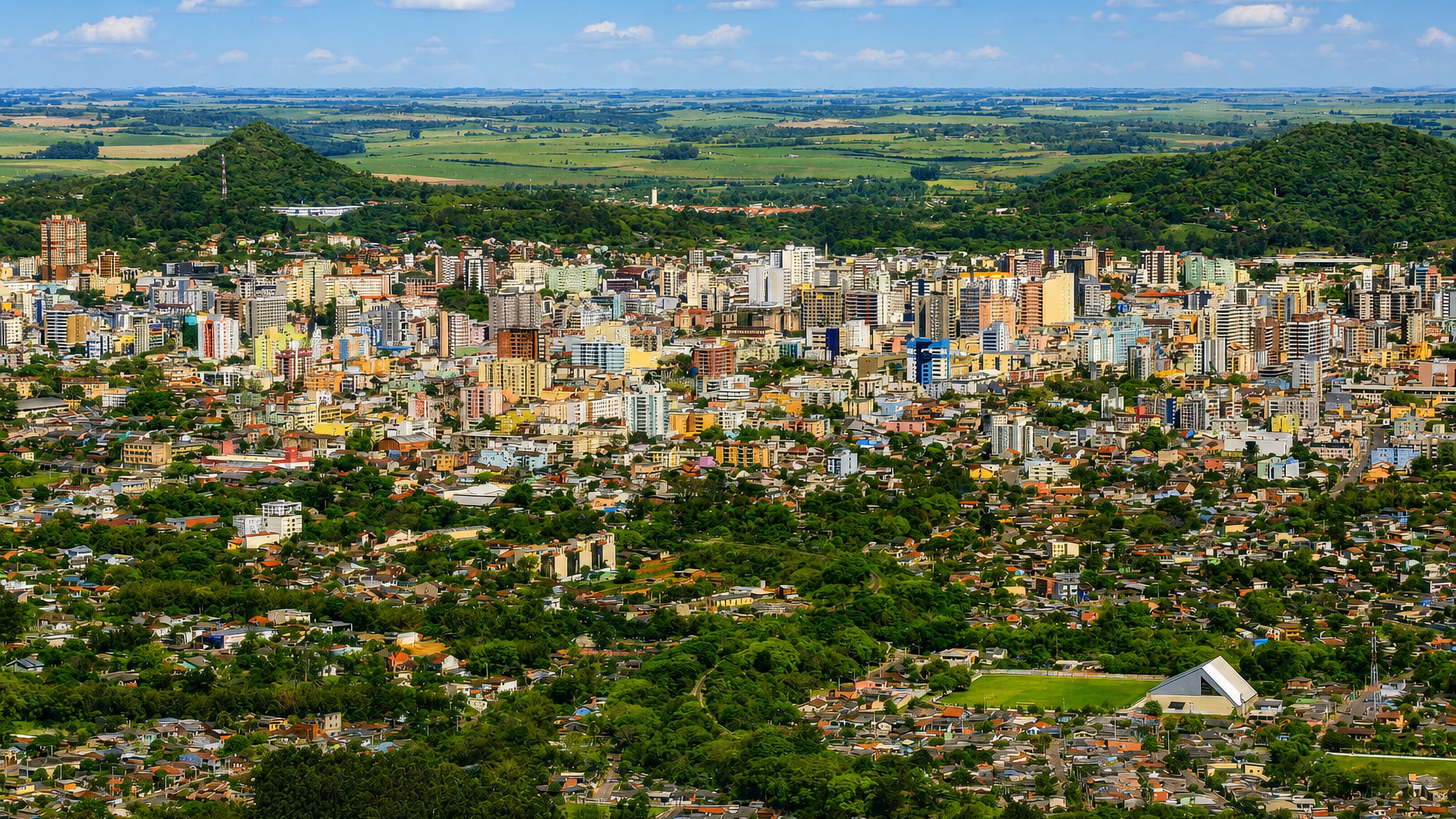 Aerial view of Santa Maria, Brazil, its dense low-rise centre spreading between green hills and farmland.