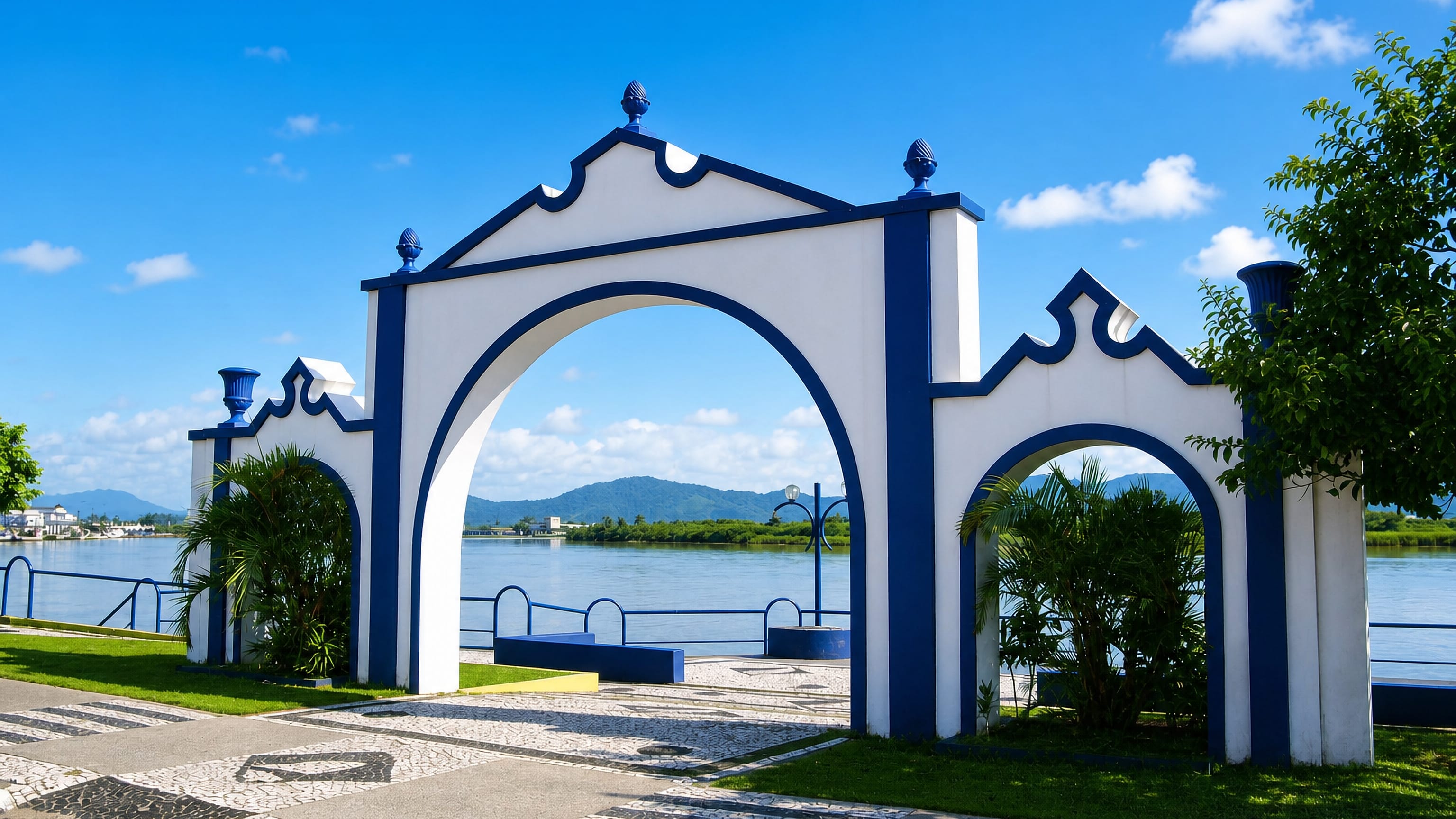 Blue-and-white ornamental portal on the Itajai riverfront in Santa Catarina, Brazil, with green hills beyond.