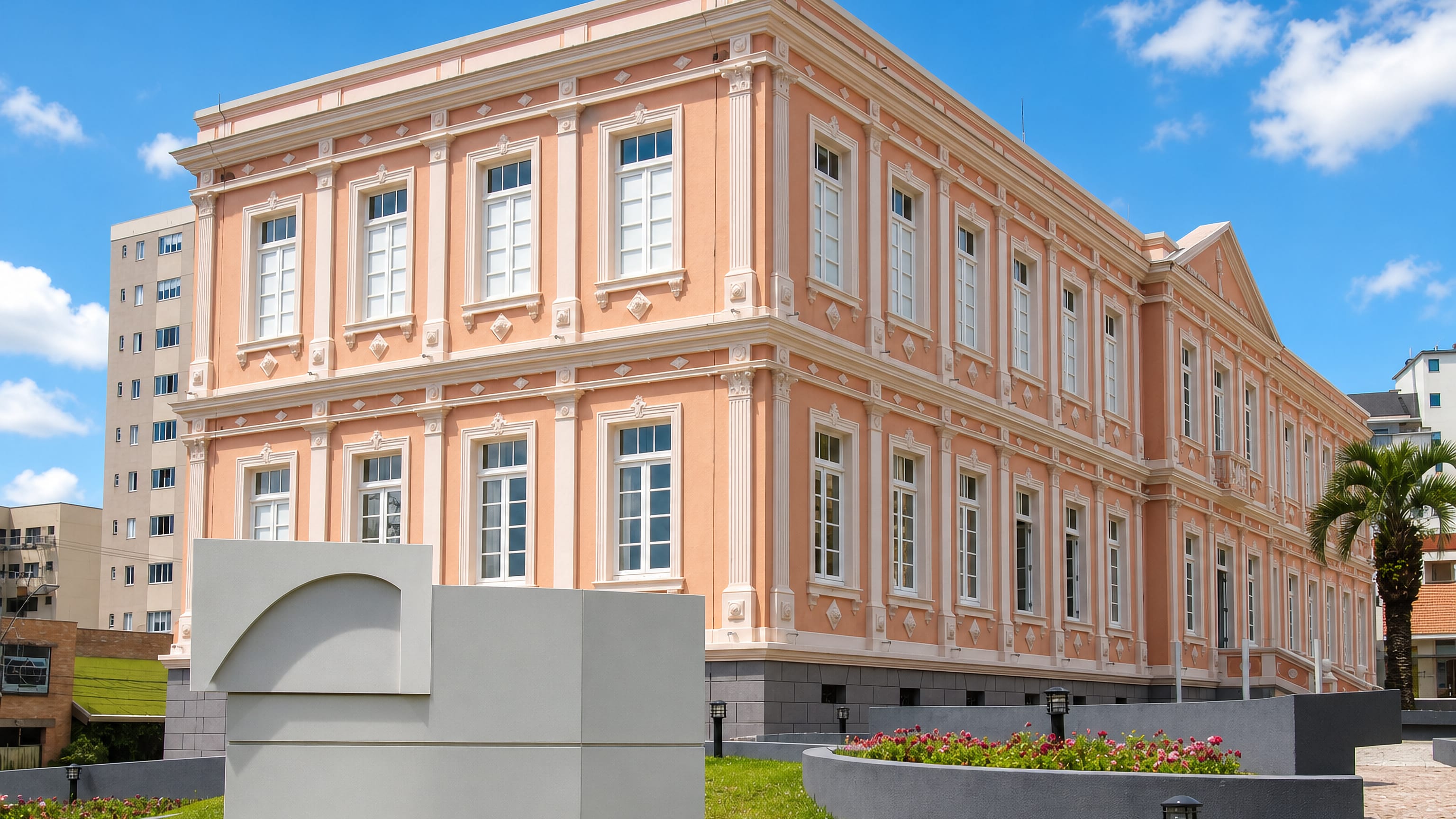 Restored salmon-pink neoclassical civic building with palms and flowerbeds in central Lages, Santa Catarina