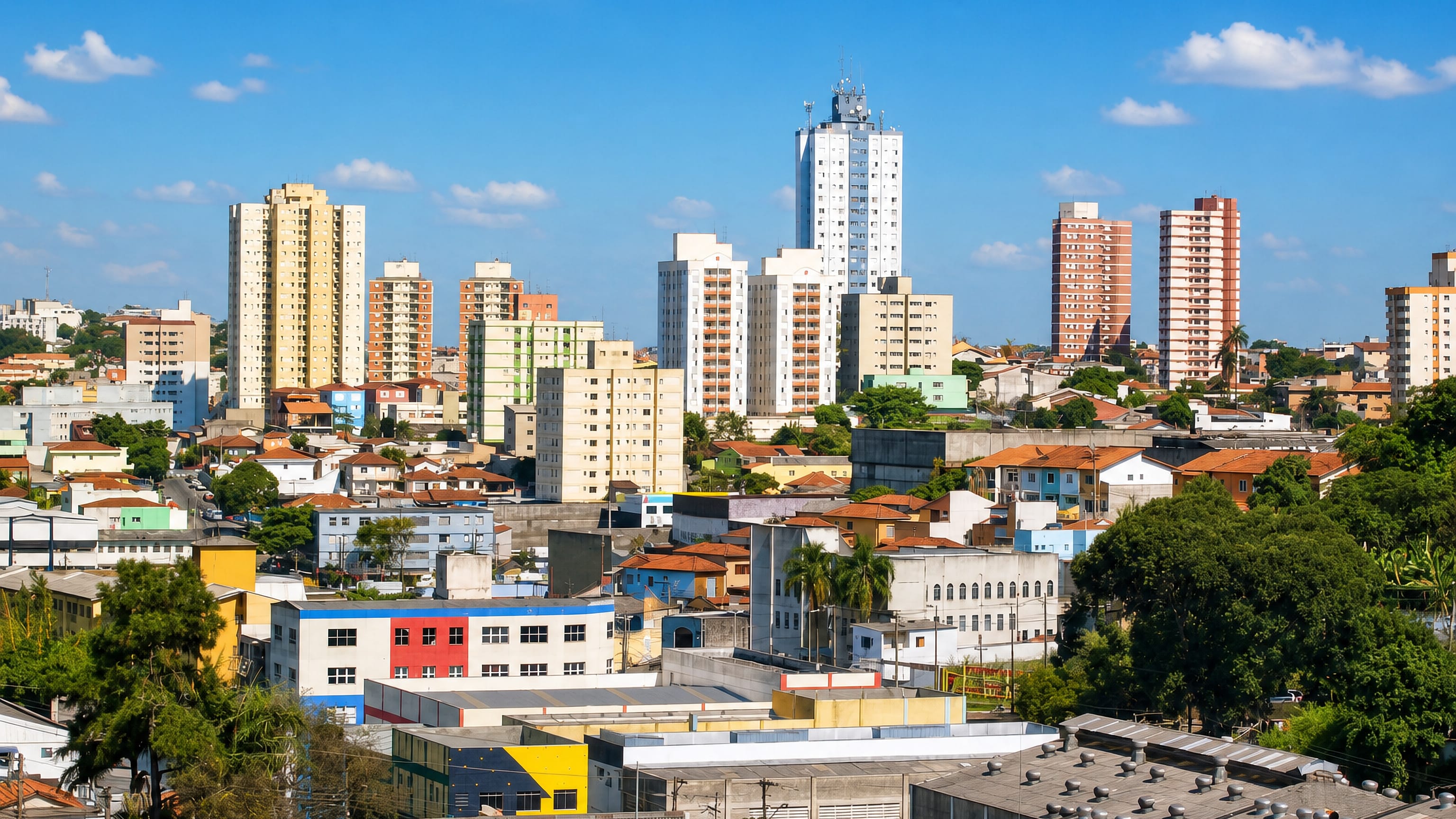 Apartment towers rising over terracotta rooftops and industrial sheds in Diadema, greater São Paulo.