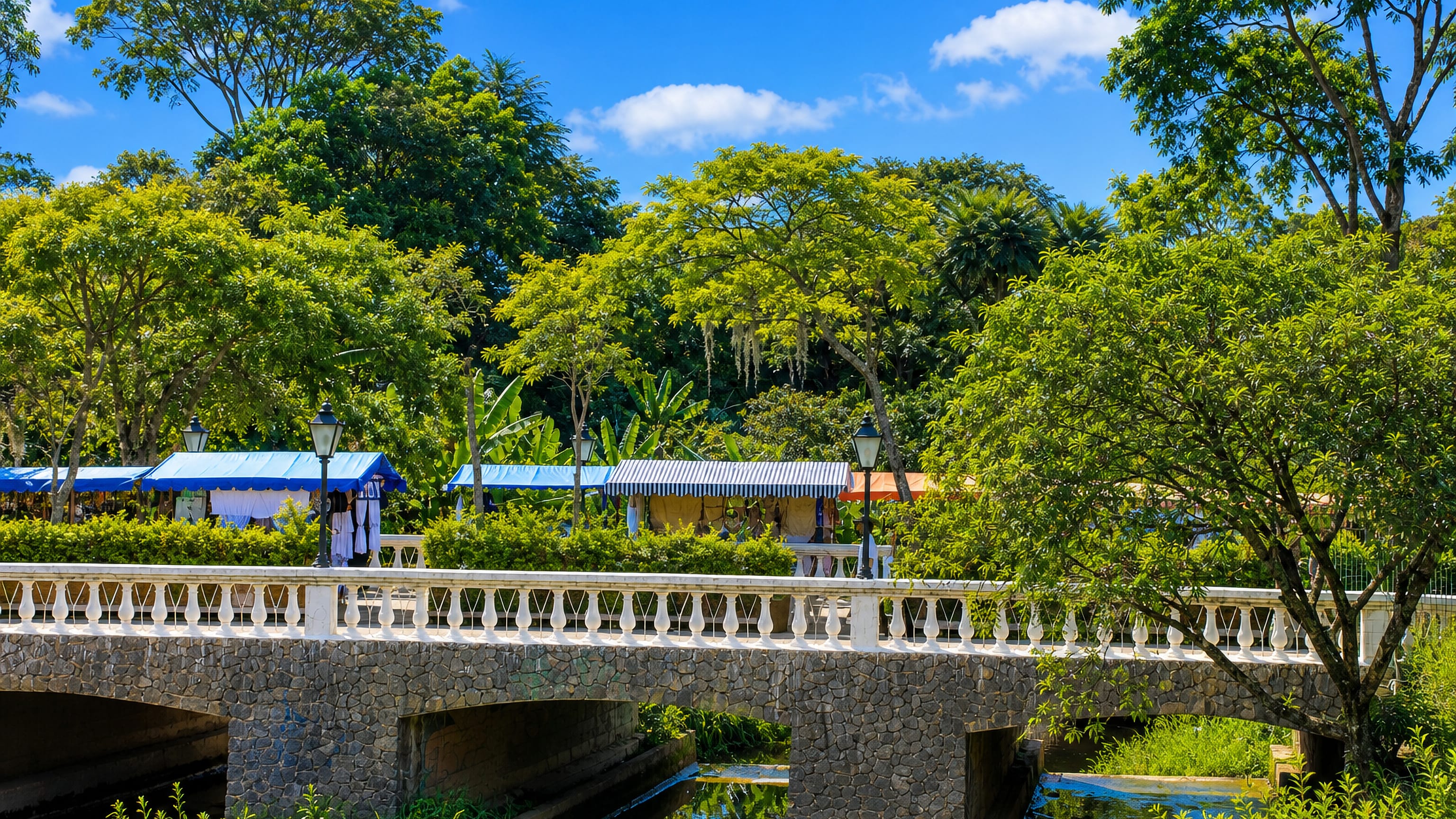 Stone bridge and craft-market stalls among leafy trees in Embu das Artes, Sao Paulo.