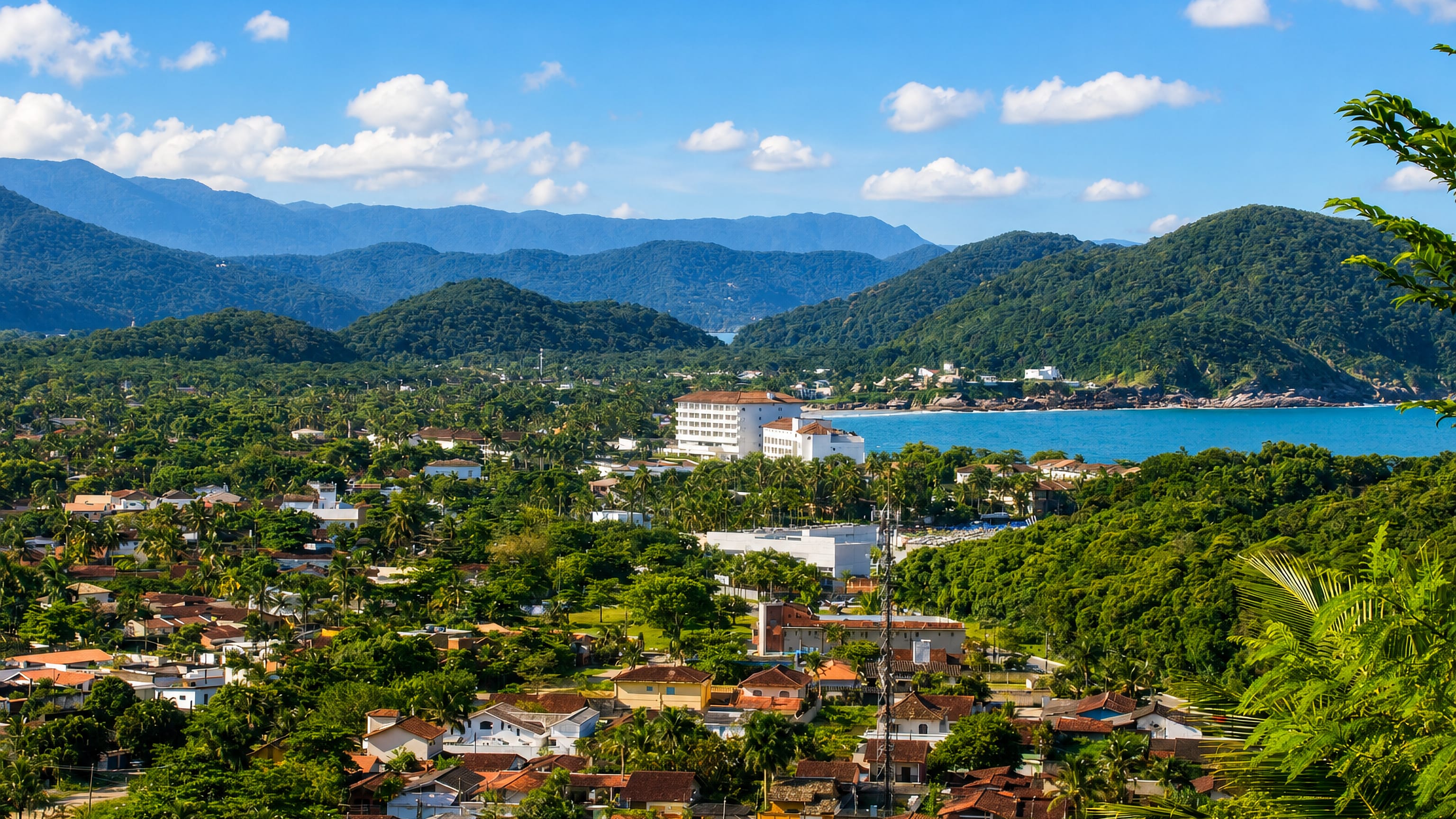 Guaruja, Brazil, seen from the hills: red-roofed streets, palm groves and Atlantic beaches below forested peaks.