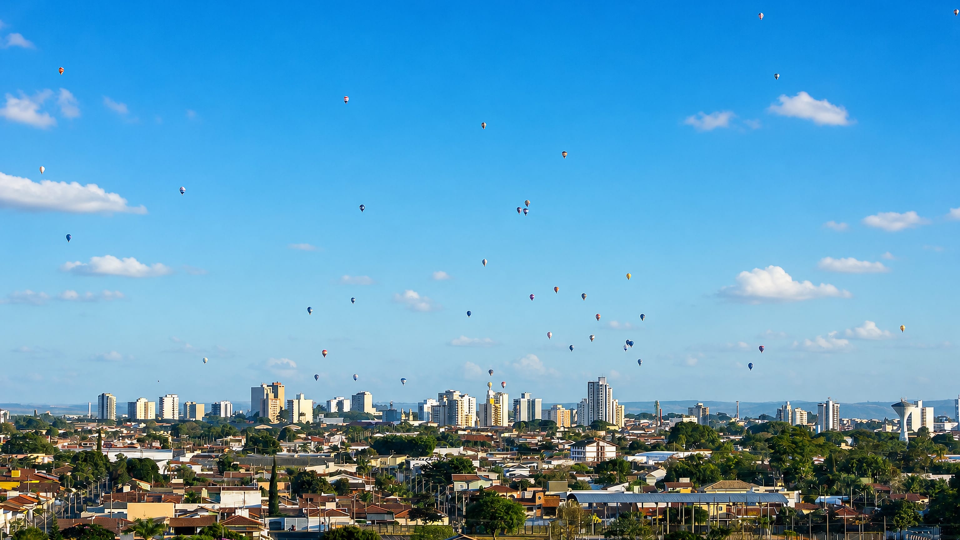 Hot-air balloons drifting over the tiled rooftops and mid-rise skyline of Rio Claro, Sao Paulo.