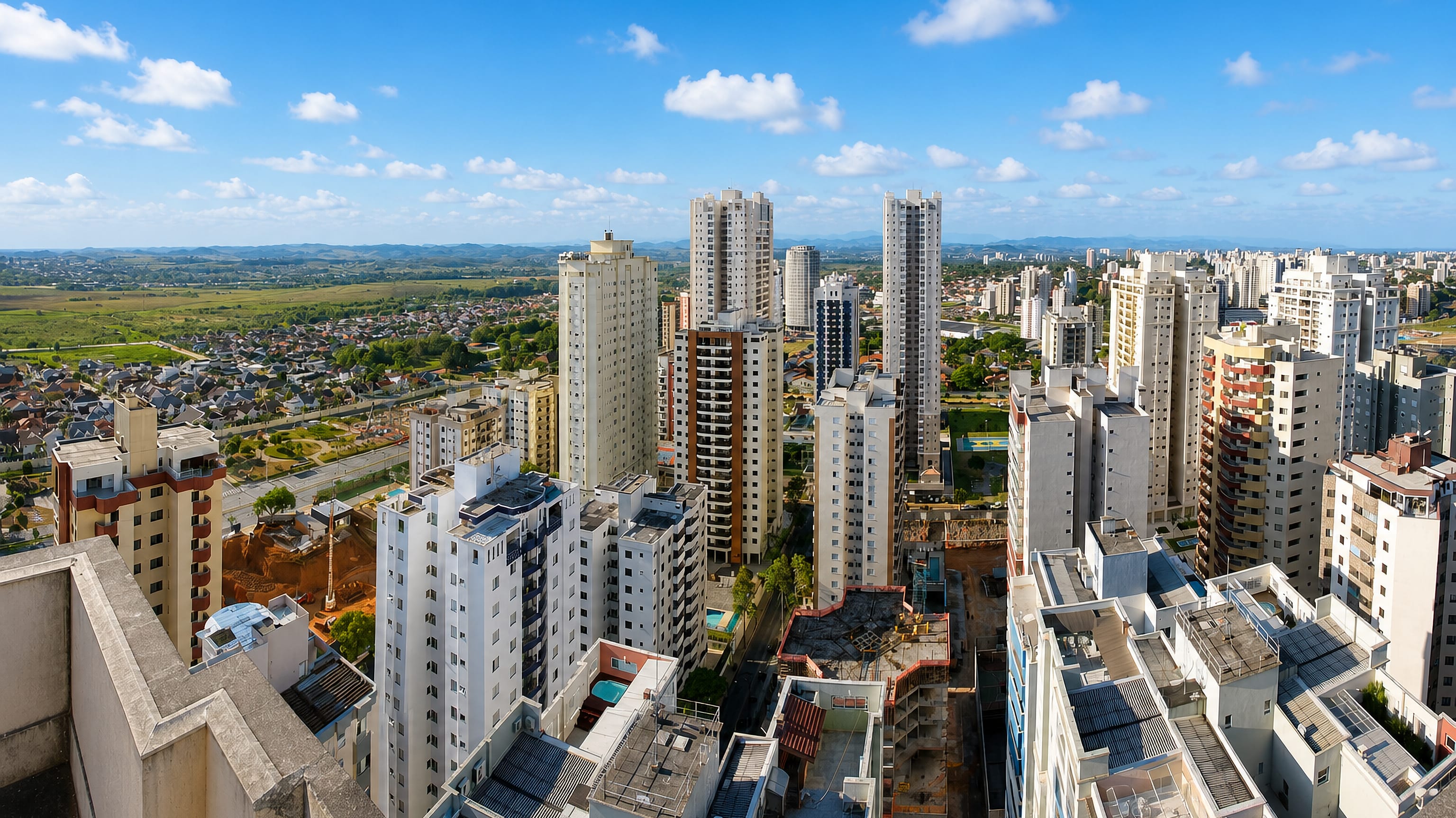 Apartment towers and rooftop pools of São José dos Campos with the Paraíba valley countryside beyond