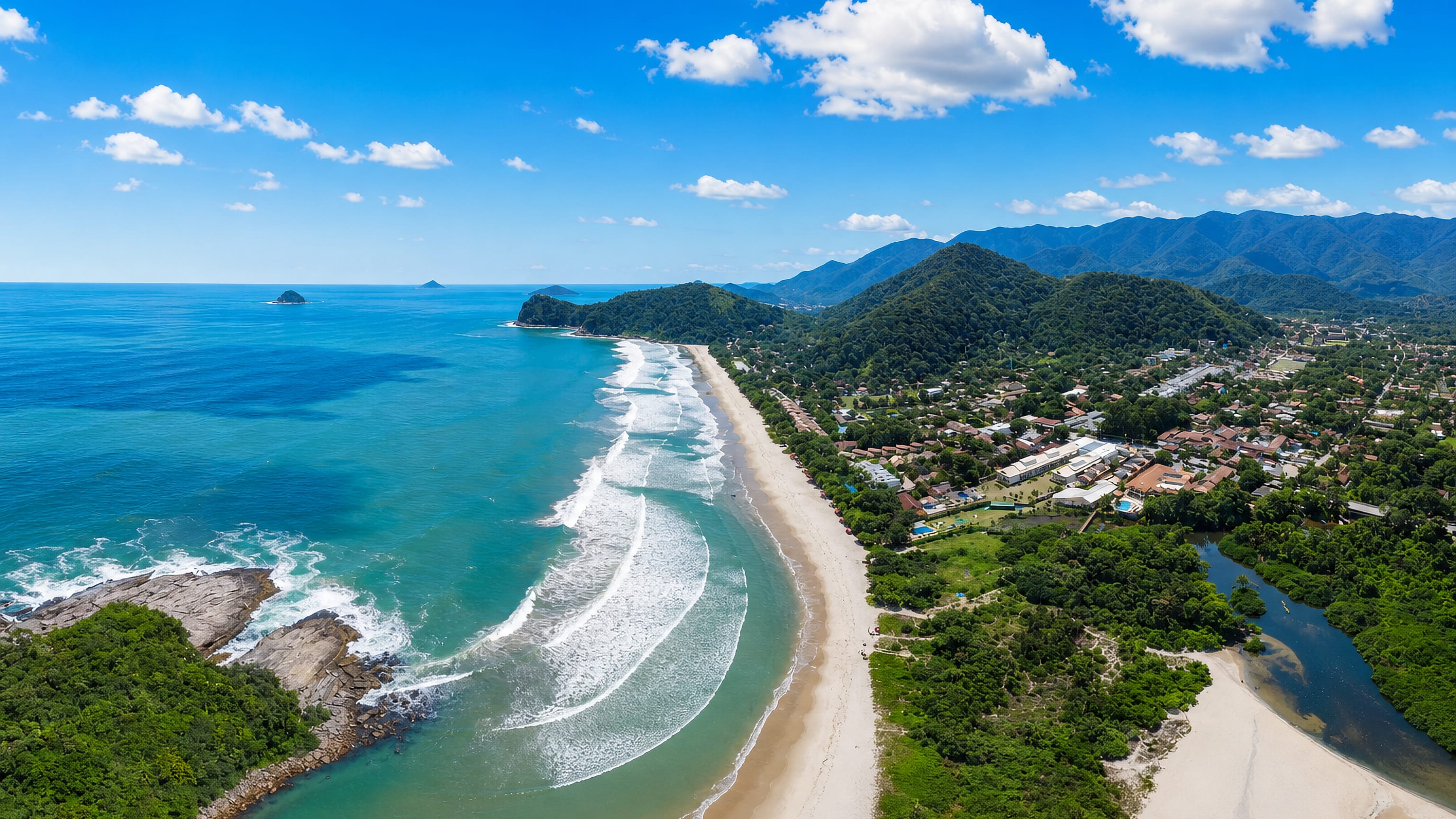 Aerial view of a curving sandy beach and forested Serra do Mar hills at São Sebastião, São Paulo, Brazil.