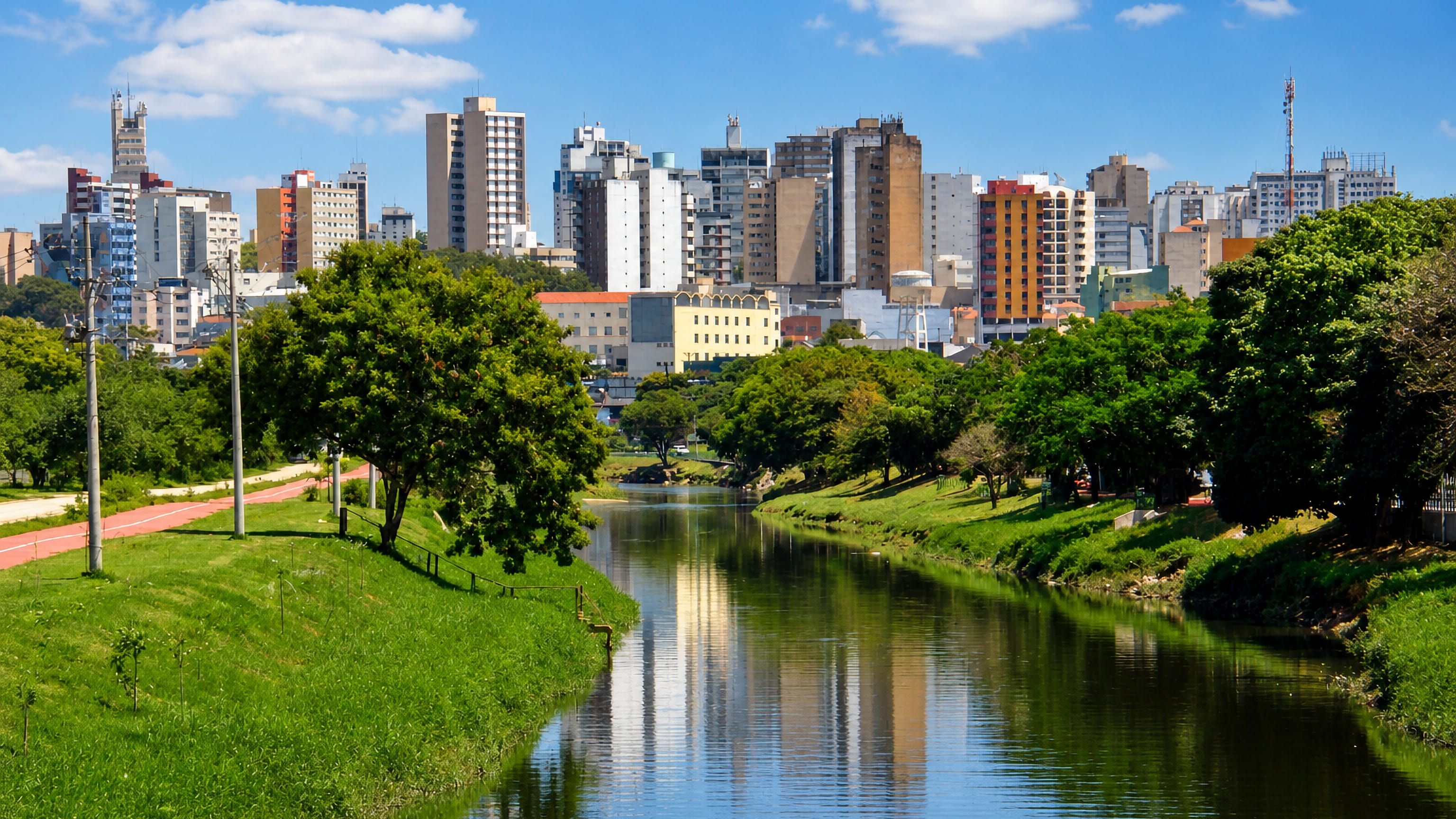 The Sorocaba River curving past green banks toward the mid-rise downtown skyline of Sorocaba, Brazil.
