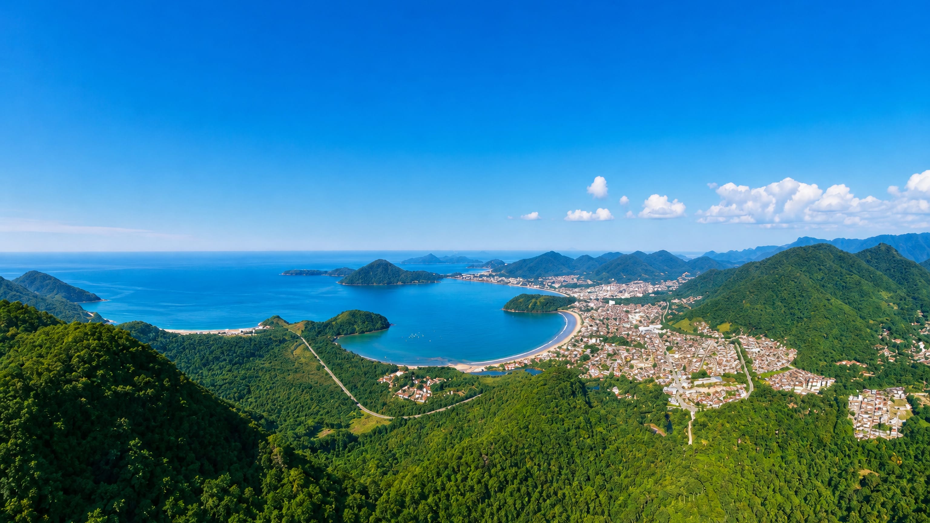 Ubatuba's crescent bay on the Sao Paulo coast, backed by Atlantic forest hills and low-rise town along the shore.