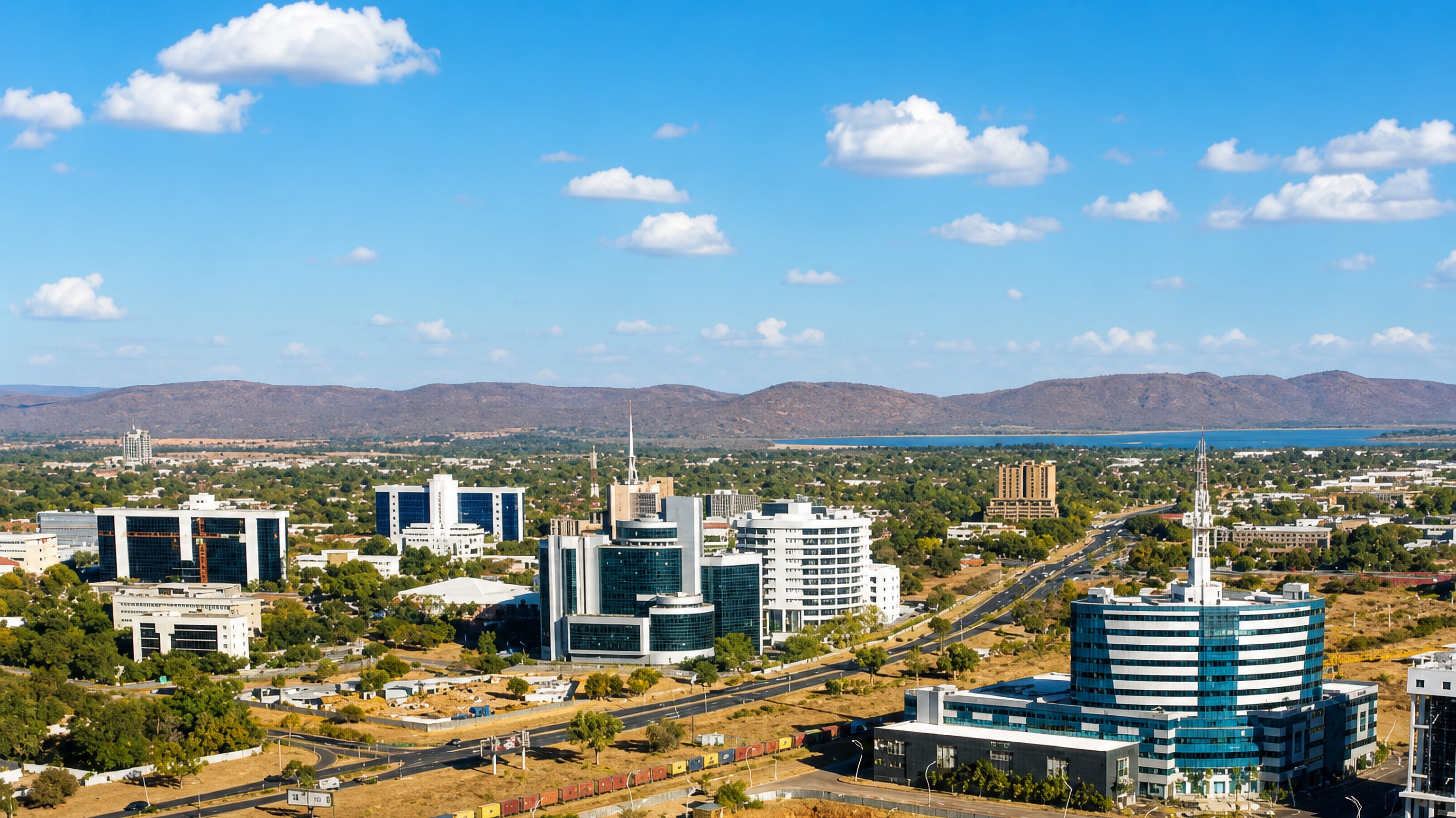 Glass office towers of Gaborone's business district rise above dry savanna and distant hills, Botswana.
