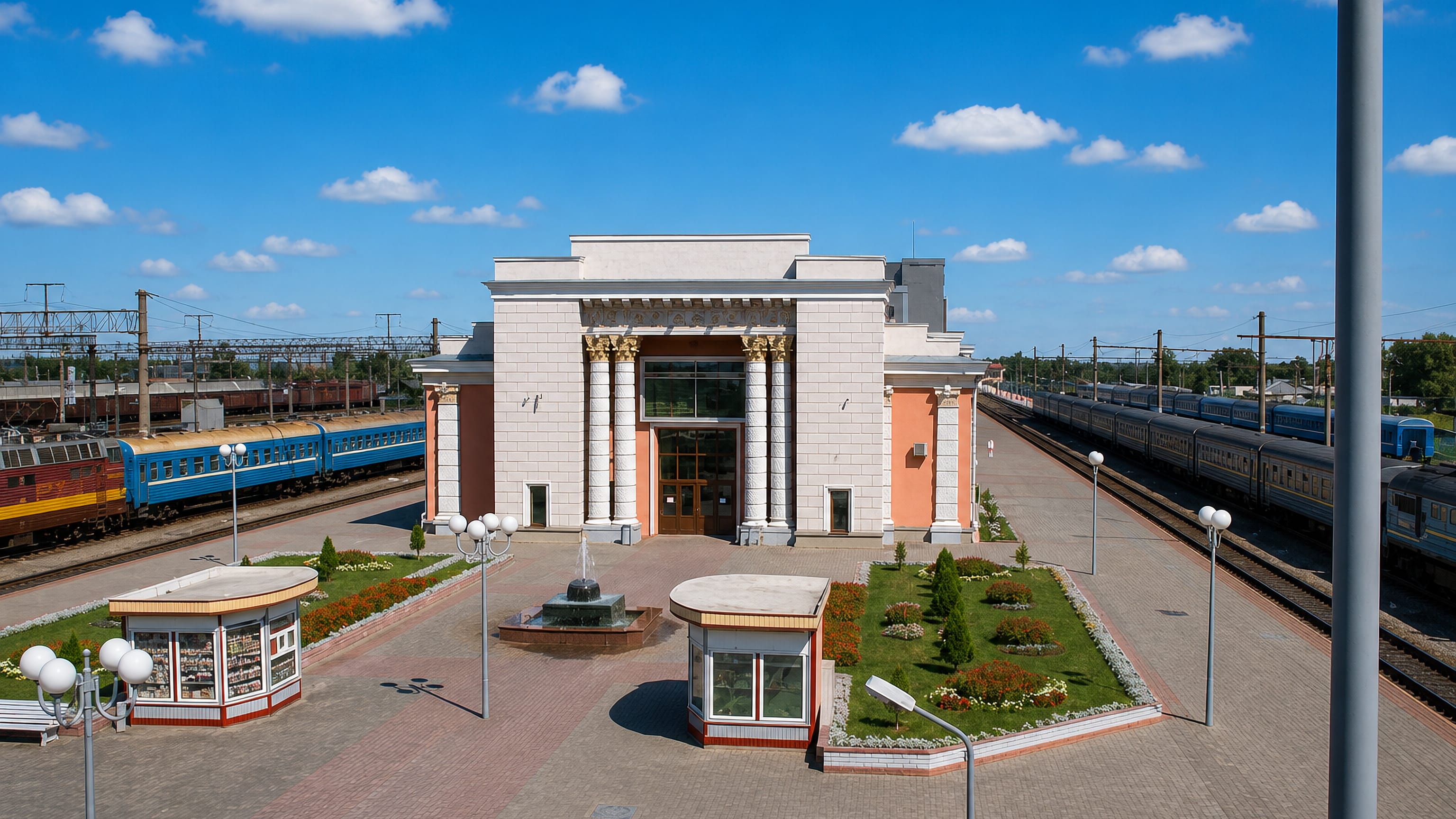 Neoclassical railway station and its landscaped forecourt with passenger trains at Orsha, Belarus.
